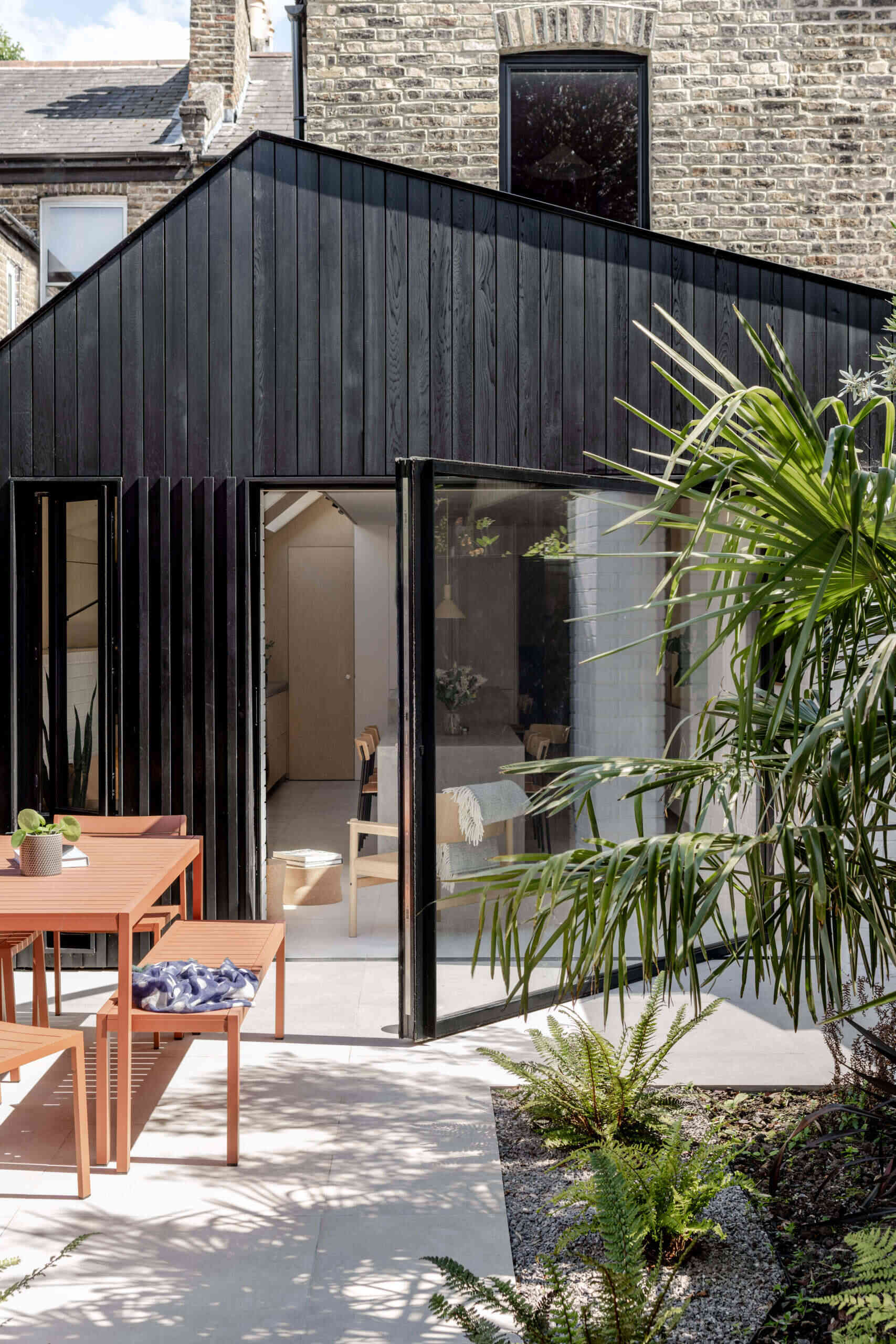Clad in blackened cedar and filled with light, the new extension opens to the garden and unites kitchen, dining, and living into one calm space.