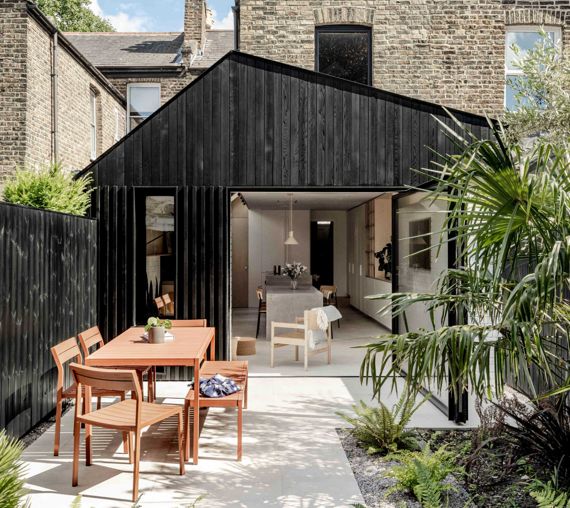 Clad in blackened cedar and filled with light, the new extension opens to the garden and unites kitchen, dining, and living into one calm space.