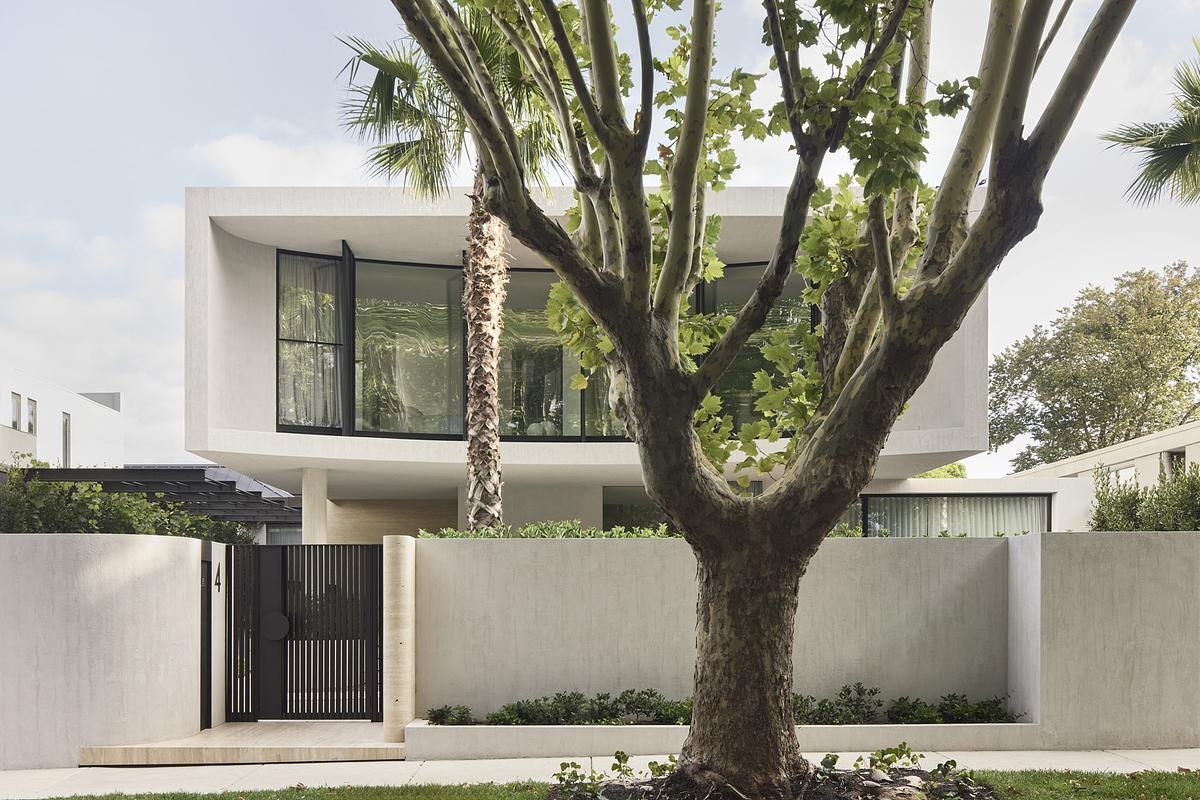 Natural rock cladding, curved forms, and expansive glazing define the sculptural exterior of this serene, modern Melbourne home.