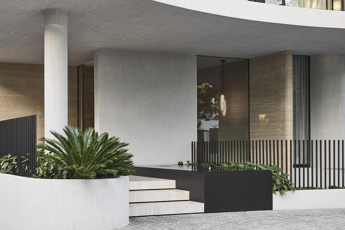Natural rock cladding, curved forms, and expansive glazing define the sculptural exterior of this serene, modern Melbourne home.