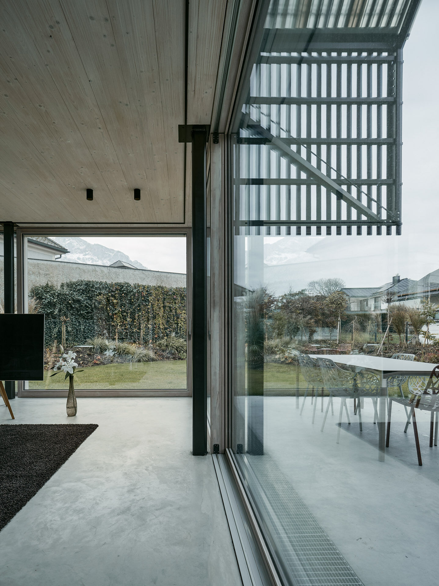 An open-plan ground floor with earthy materials and full-height glass doors connects the interior seamlessly to the garden.