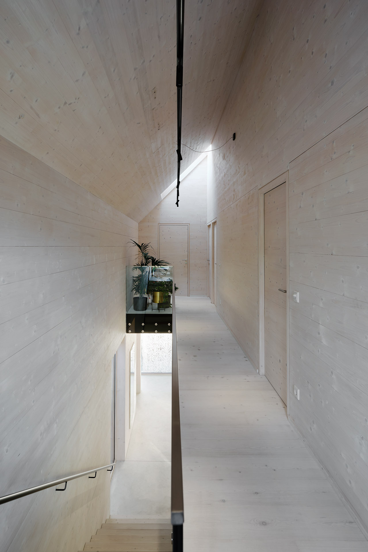 Light wood walls, floors, and a sloped ceiling create a warm, cohesive stairwell that softly guides you upstairs.