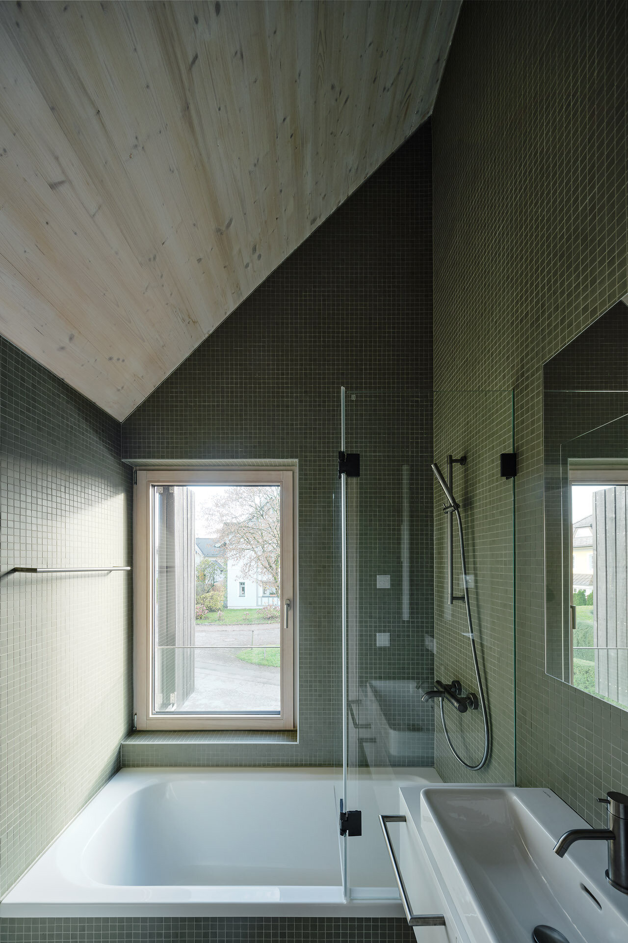 Green mosaic tiles and a timber-lined ceiling bring texture and calm to this serene, light-filled bathroom.