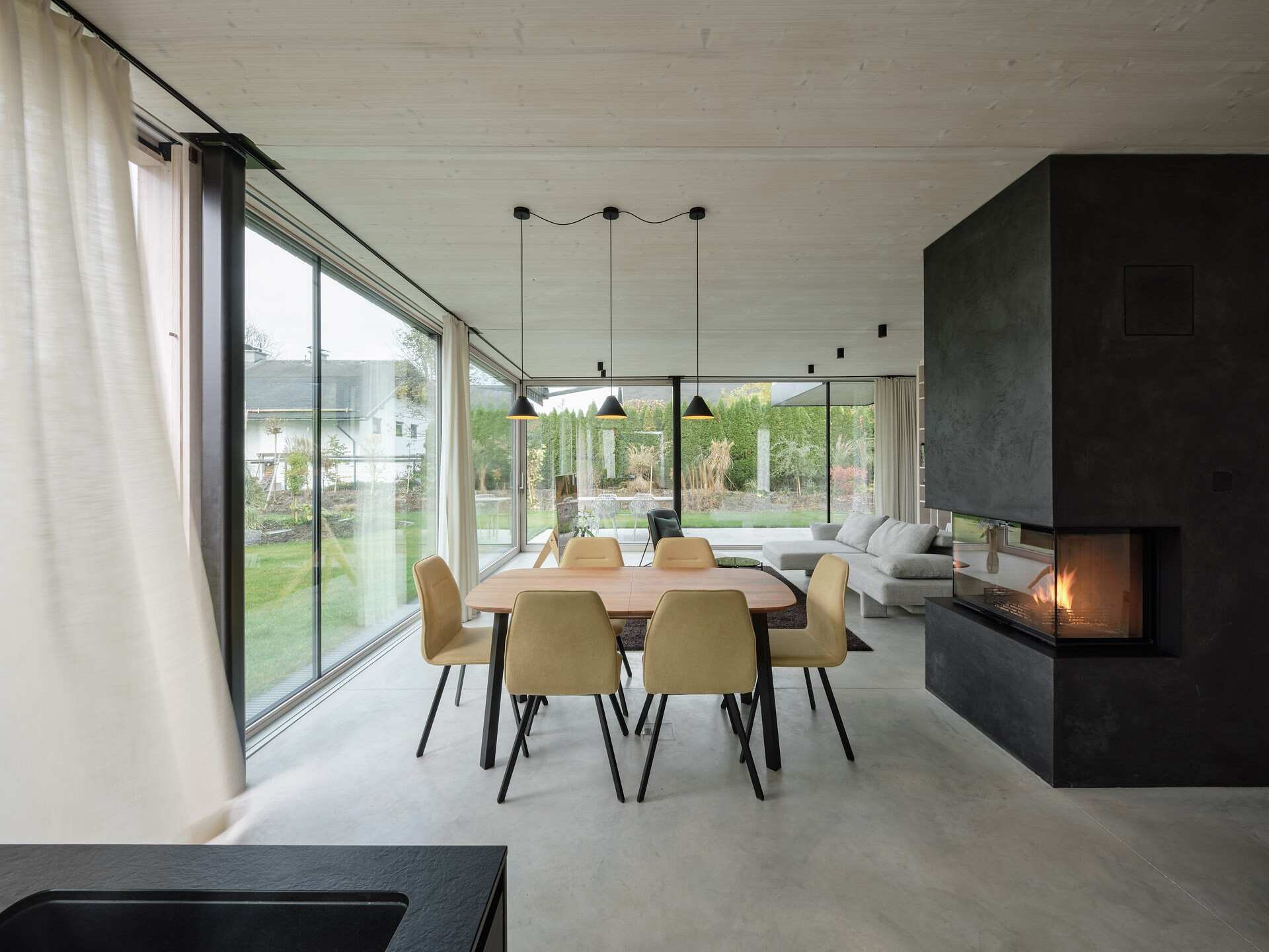 An open-plan ground floor with earthy materials and full-height glass doors connects the interior seamlessly to the garden.