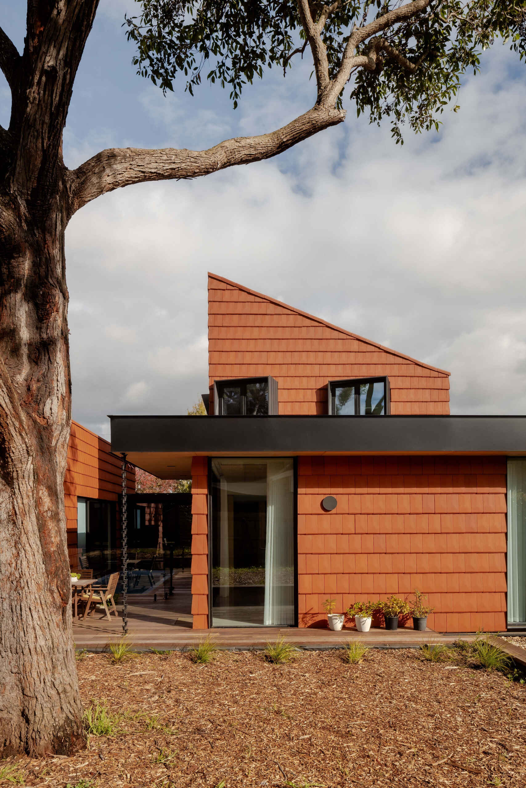 Discover how this Melbourne home uses terracotta shingles on both roof and walls, blending sustainable materials with a warm, natural palette rooted in the surrounding trees.