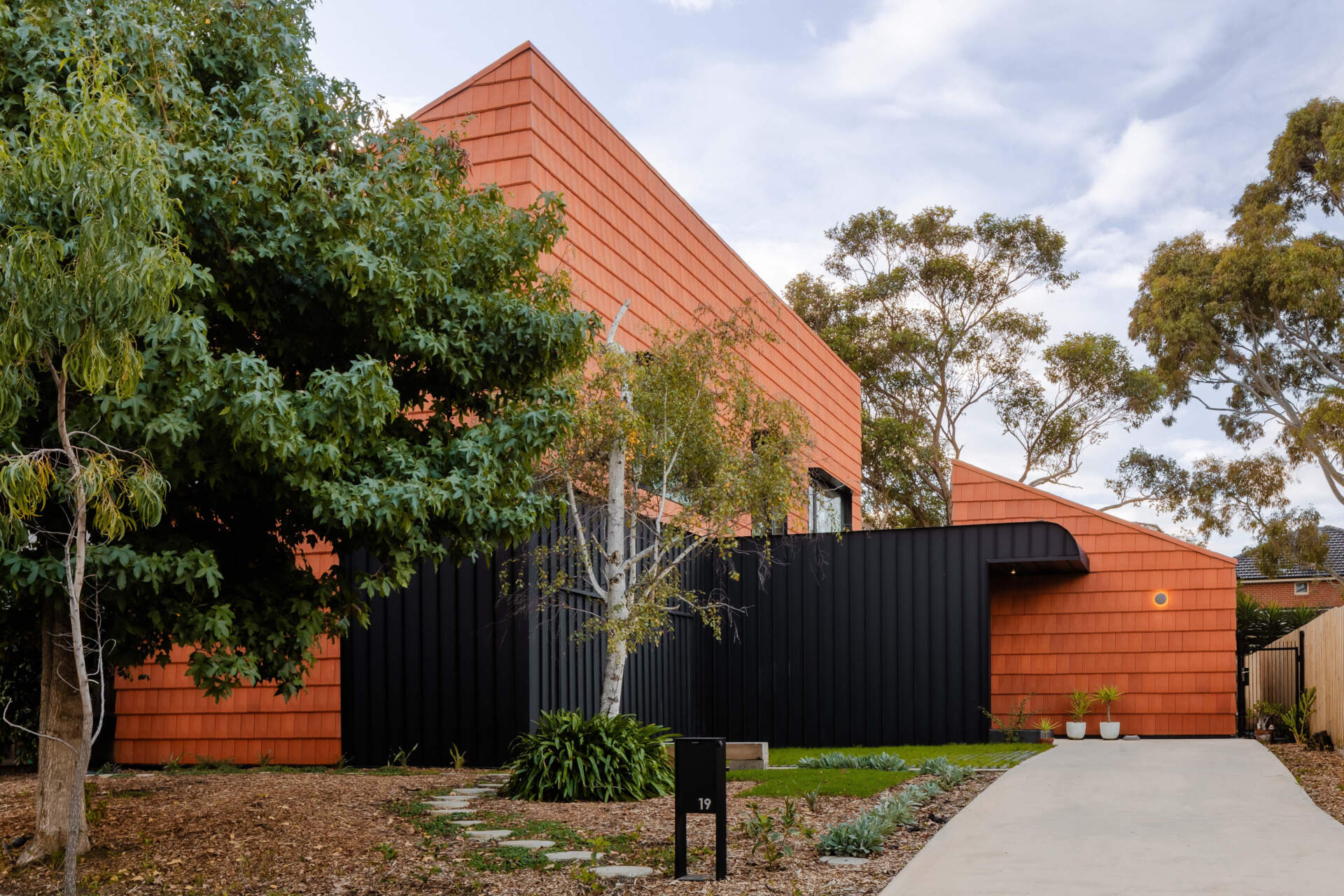 Discover how this Melbourne home uses terracotta shingles on both roof and walls, blending sustainable materials with a warm, natural palette rooted in the surrounding trees.