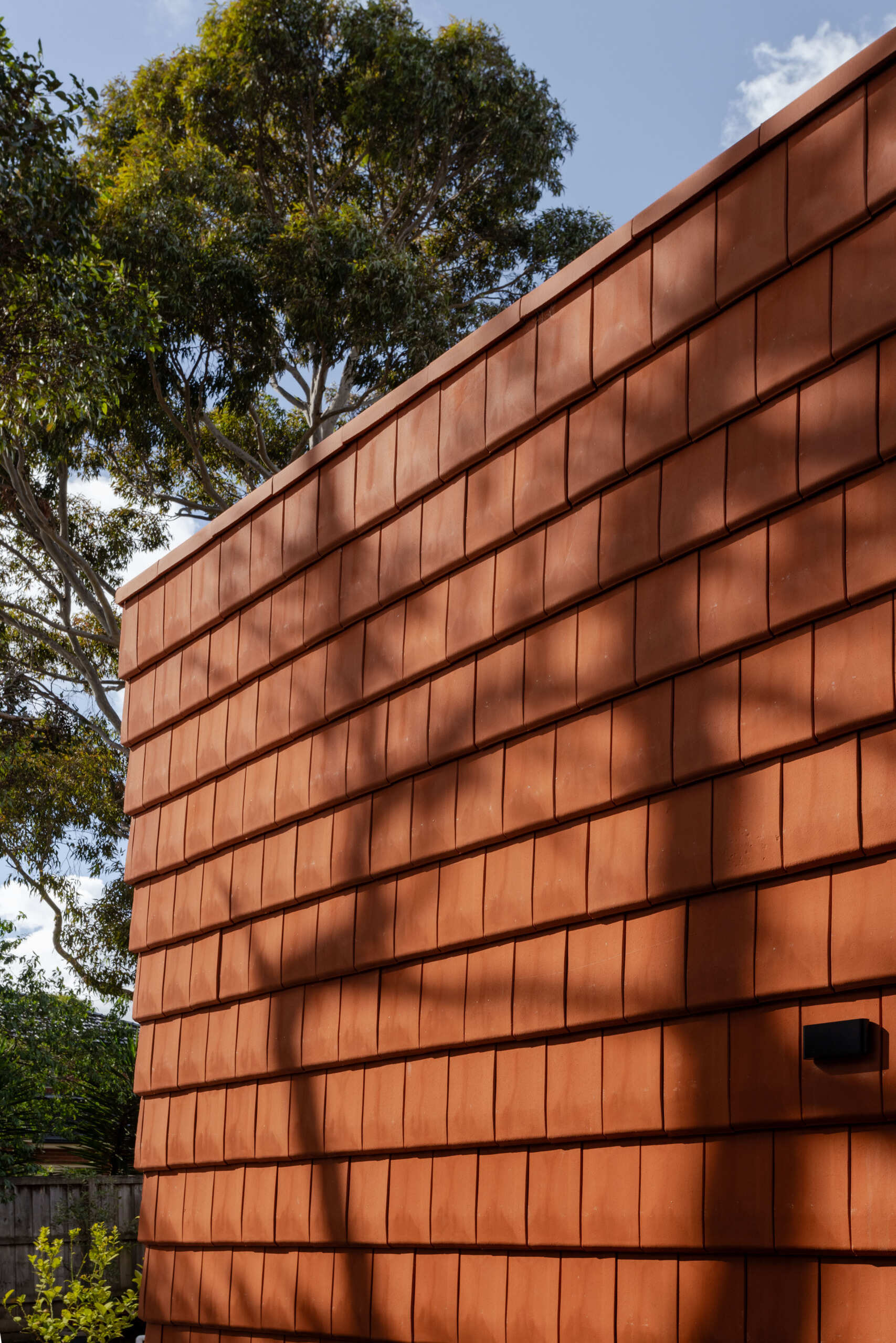 Discover how this Melbourne home uses terracotta shingles on both roof and walls, blending sustainable materials with a warm, natural palette rooted in the surrounding trees.