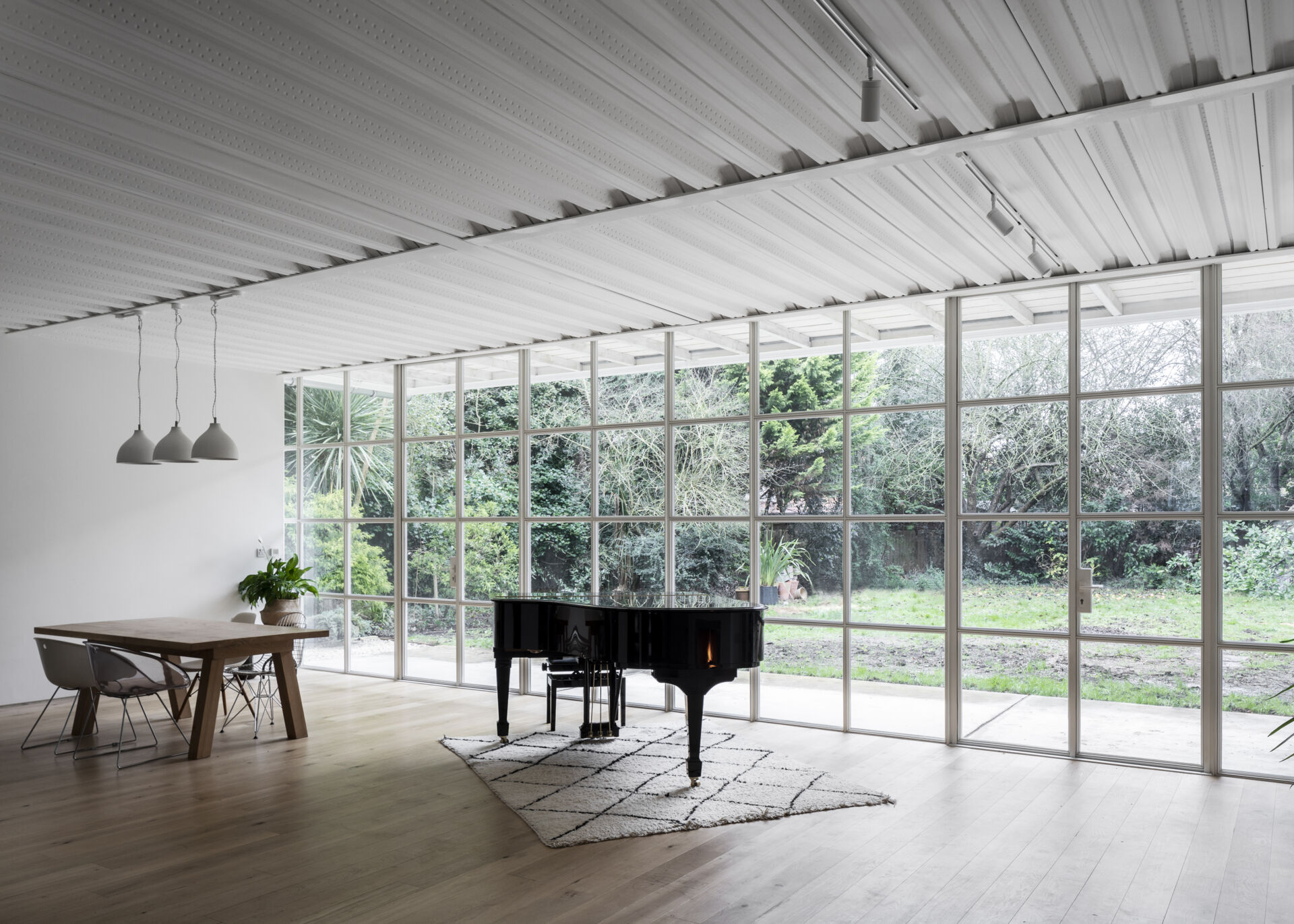 Warm timber floors meet cool steel details in this open-plan living space, where panoramic Crittall-style windows bring the garden right into view.