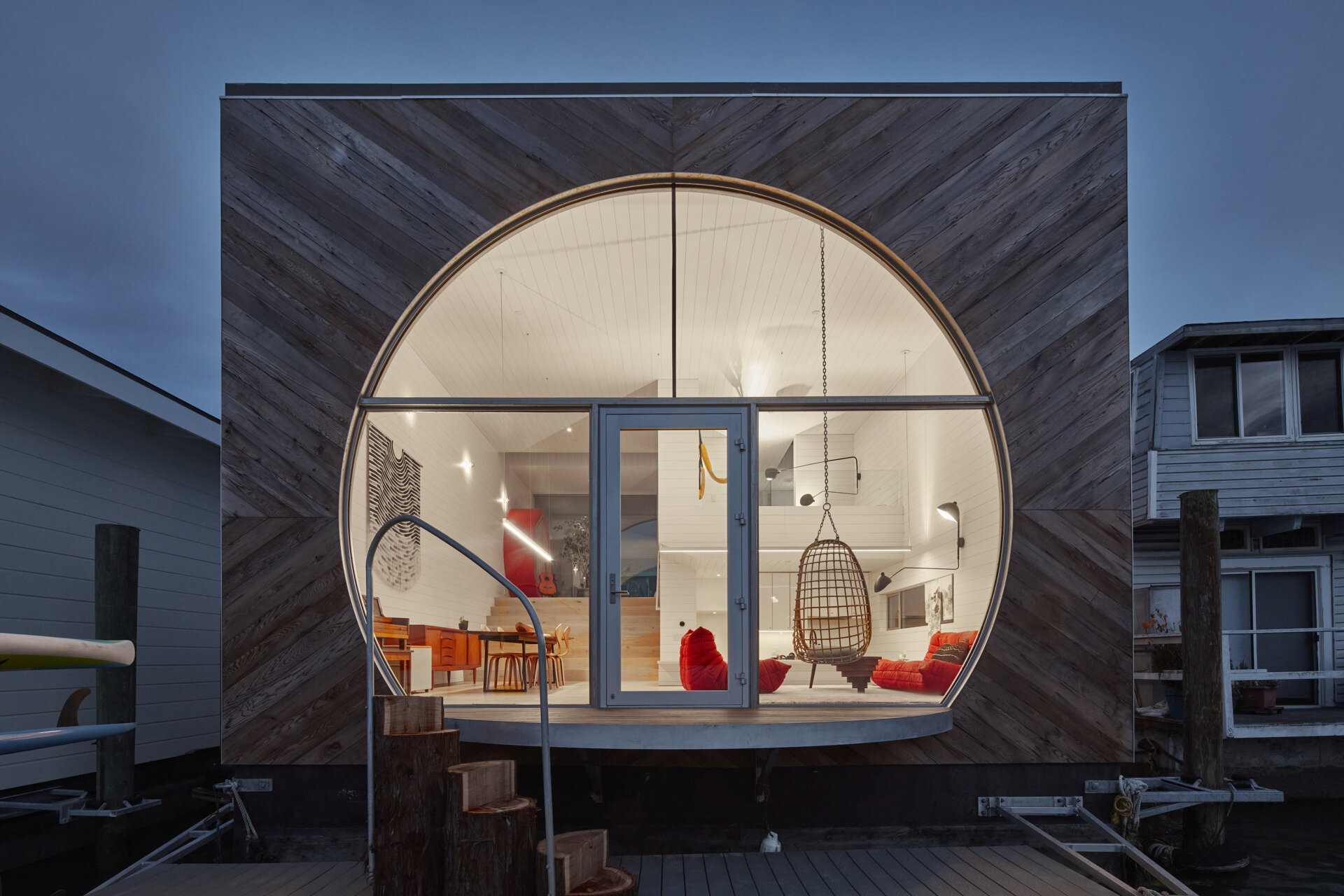 This modern houseboat showcases authentic waterfront living through its compact, efficient design. Featuring natural wood, weathered metal, and expansive glass, the layered structure blends seamlessly with its environment while honoring the community’s experimental roots.