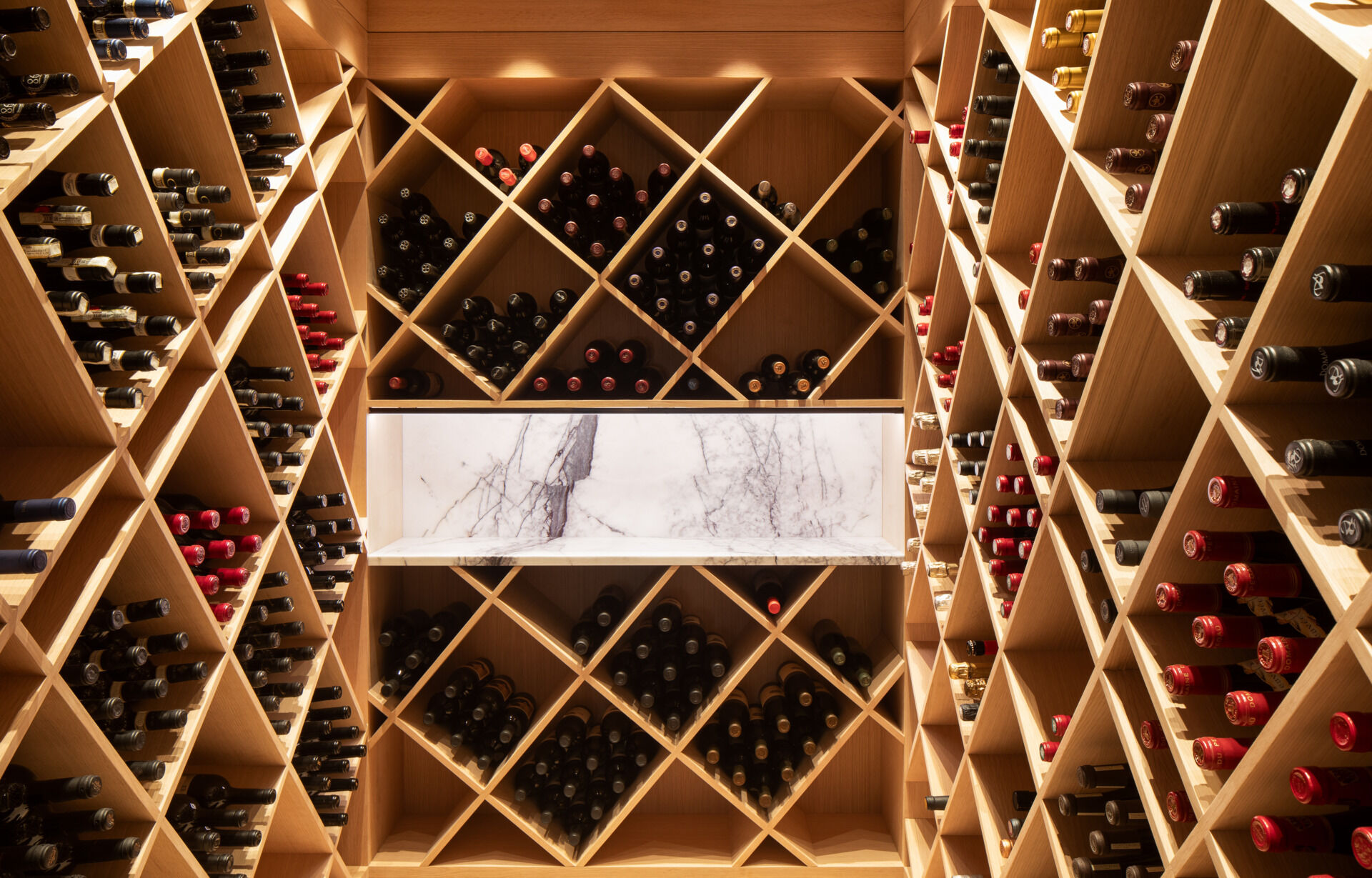 Tucked away from the main living spaces, the wine cellar embraces quiet refinement. Warm wood shelving, arranged in geometric harmony, cradles each bottle with care.