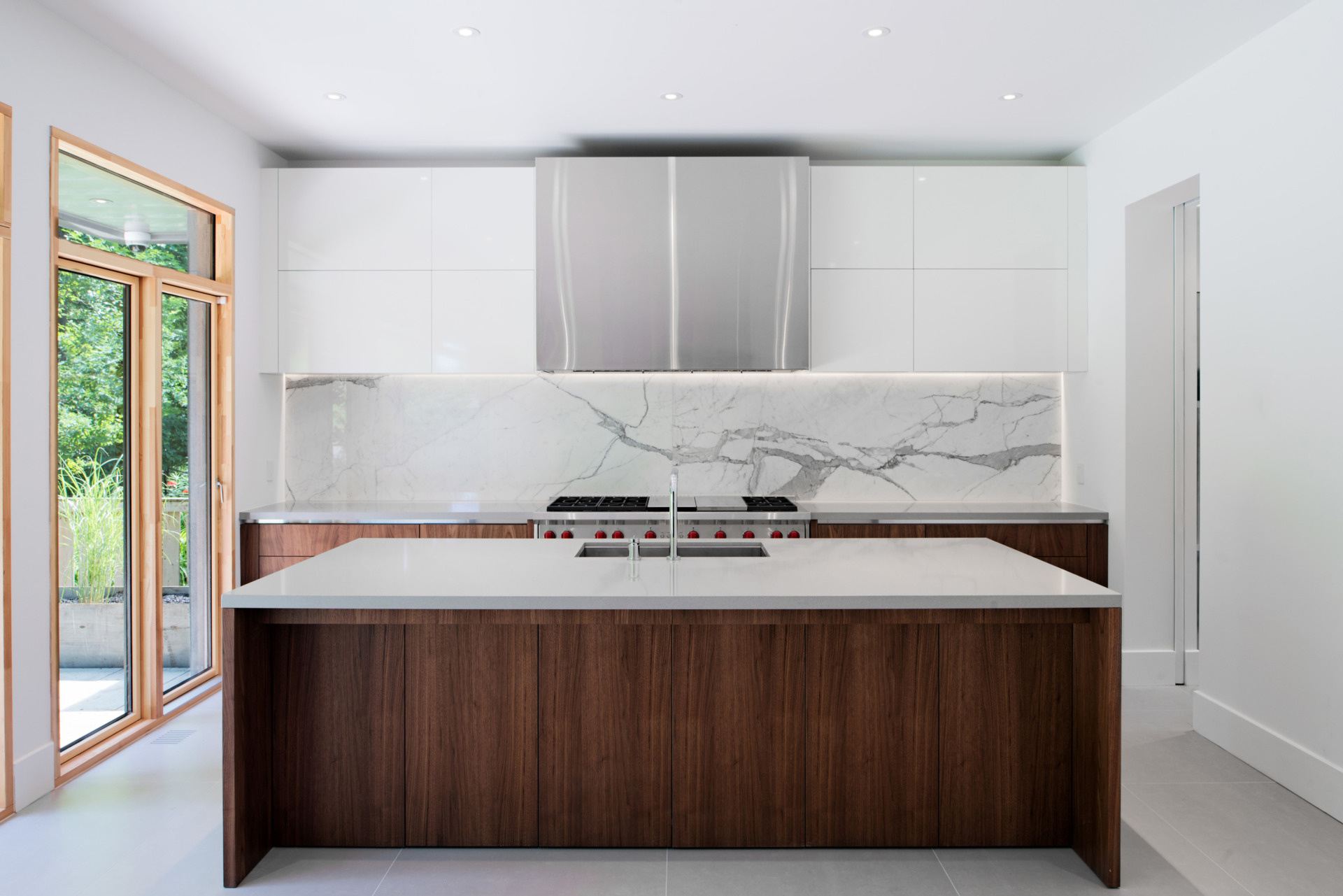 A warm wood accent wall anchors the family room in this open-concept main floor. With a wood dining table and seamless flow into the kitchen, the space feels both grounded and connected.