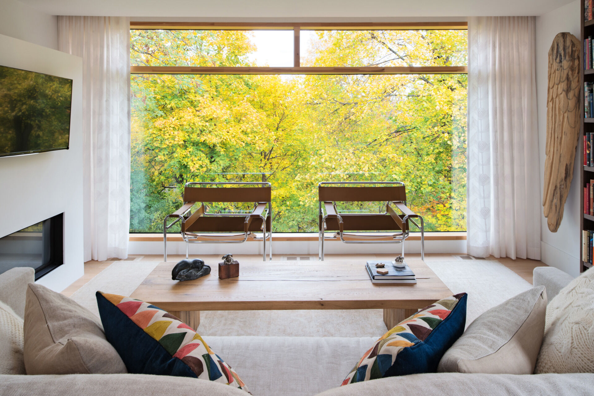 The upper-level study is a peaceful retreat with a large picture window framing ravine views. Featuring cozy bookshelves, a round table, and access to a rooftop deck, it blends comfort with nature.