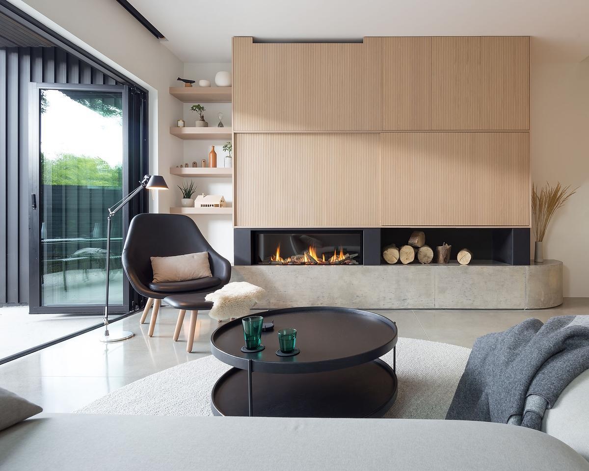 A clean-lined fireplace with a concrete base grounds this serene living space, while built-in cabinetry hides the TV for a clutter-free feel.