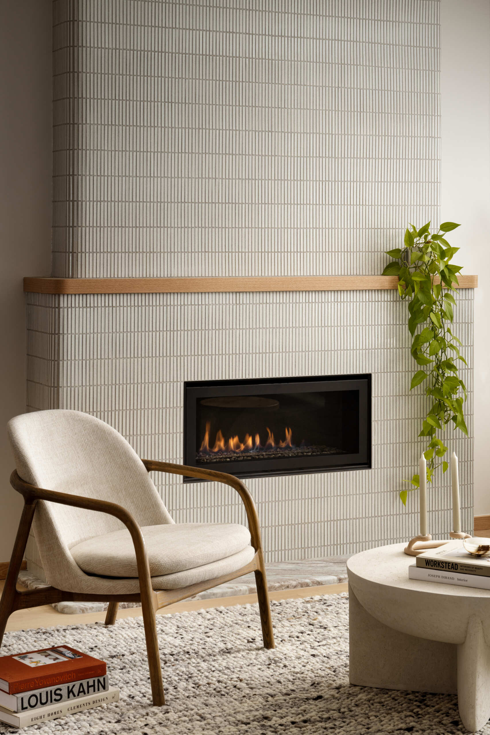 Anchoring the family room is a fireplace clad in slender Kit Kat-style tiles, adding both texture and subtle movement to the space. The vertical lines of the tile echo the curved forms used throughout the home, offering a modern yet inviting focal point. Rather than dominating the room, the fireplace quietly grounds it, warm, sculptural, and refined.