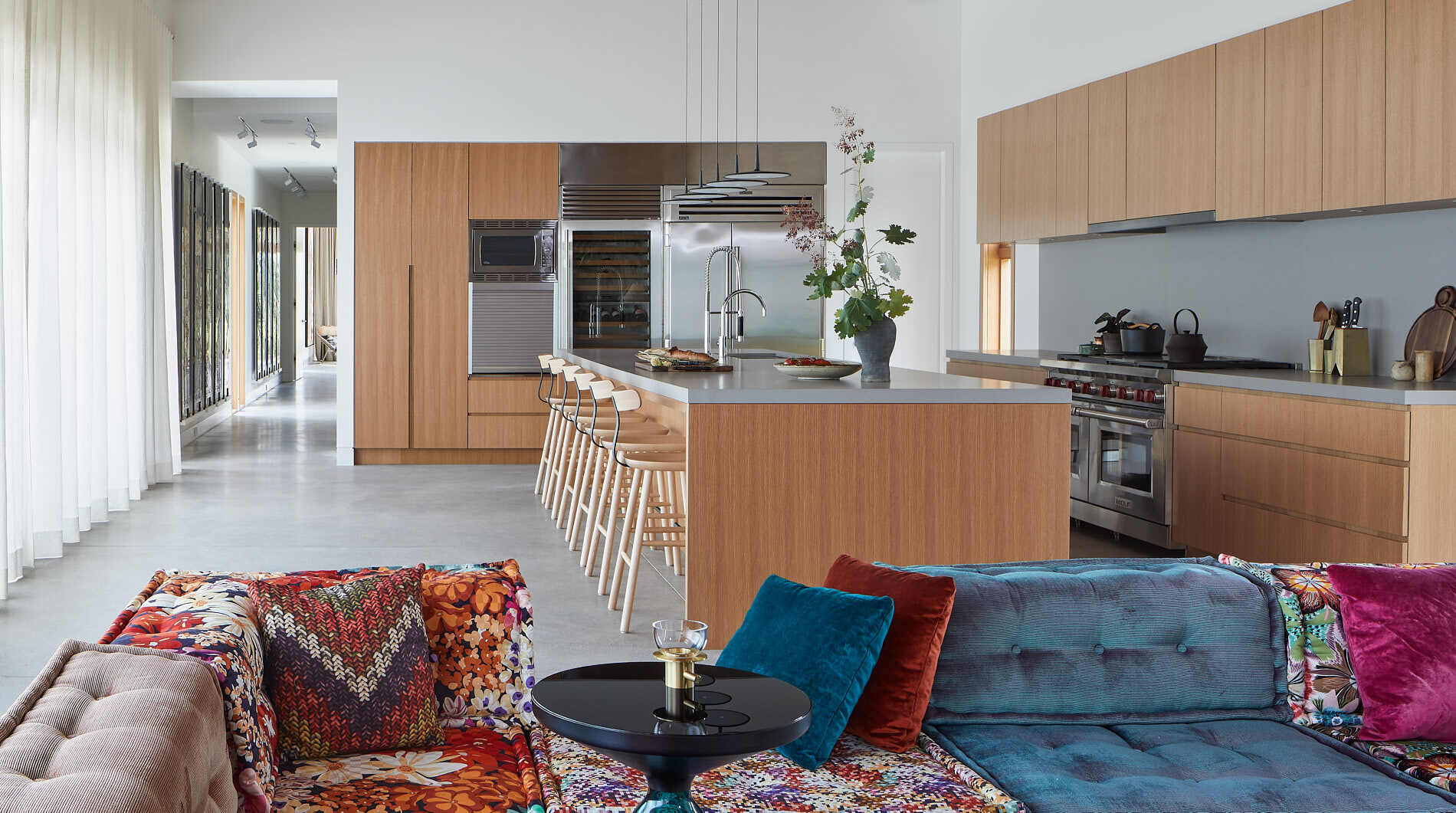 Warm minimalism defines this living room and kitchen, with a central fireplace, white oak finishes, and exposed Douglas fir beams.