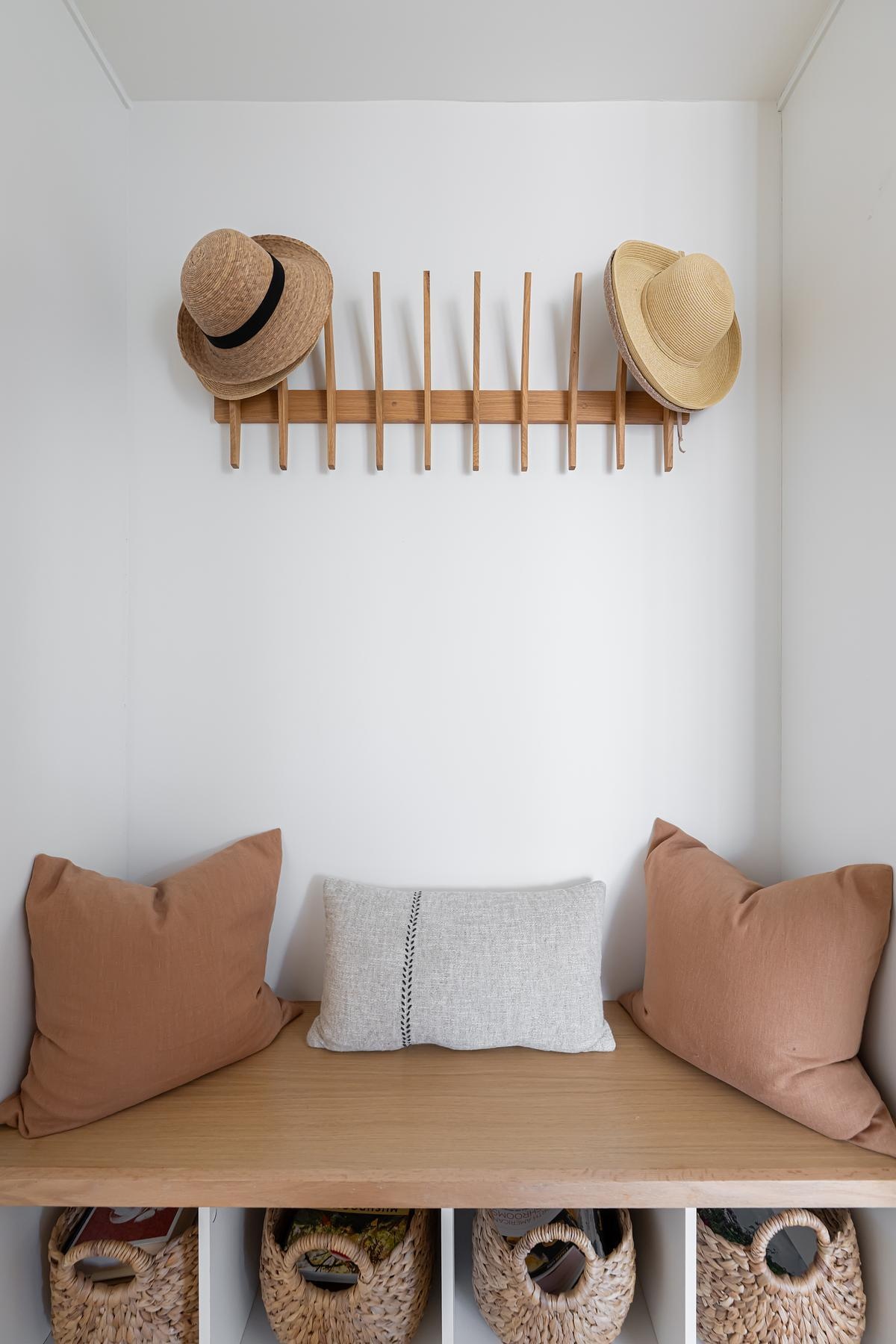 Off to the side of the front door and down a small hallway, a simple bench provides a practical spot to sit or remove shoes, with built-in storage to keep the space clutter-free. This understated feature supports the home’s clean, minimal aesthetic while addressing everyday needs with quiet efficiency.