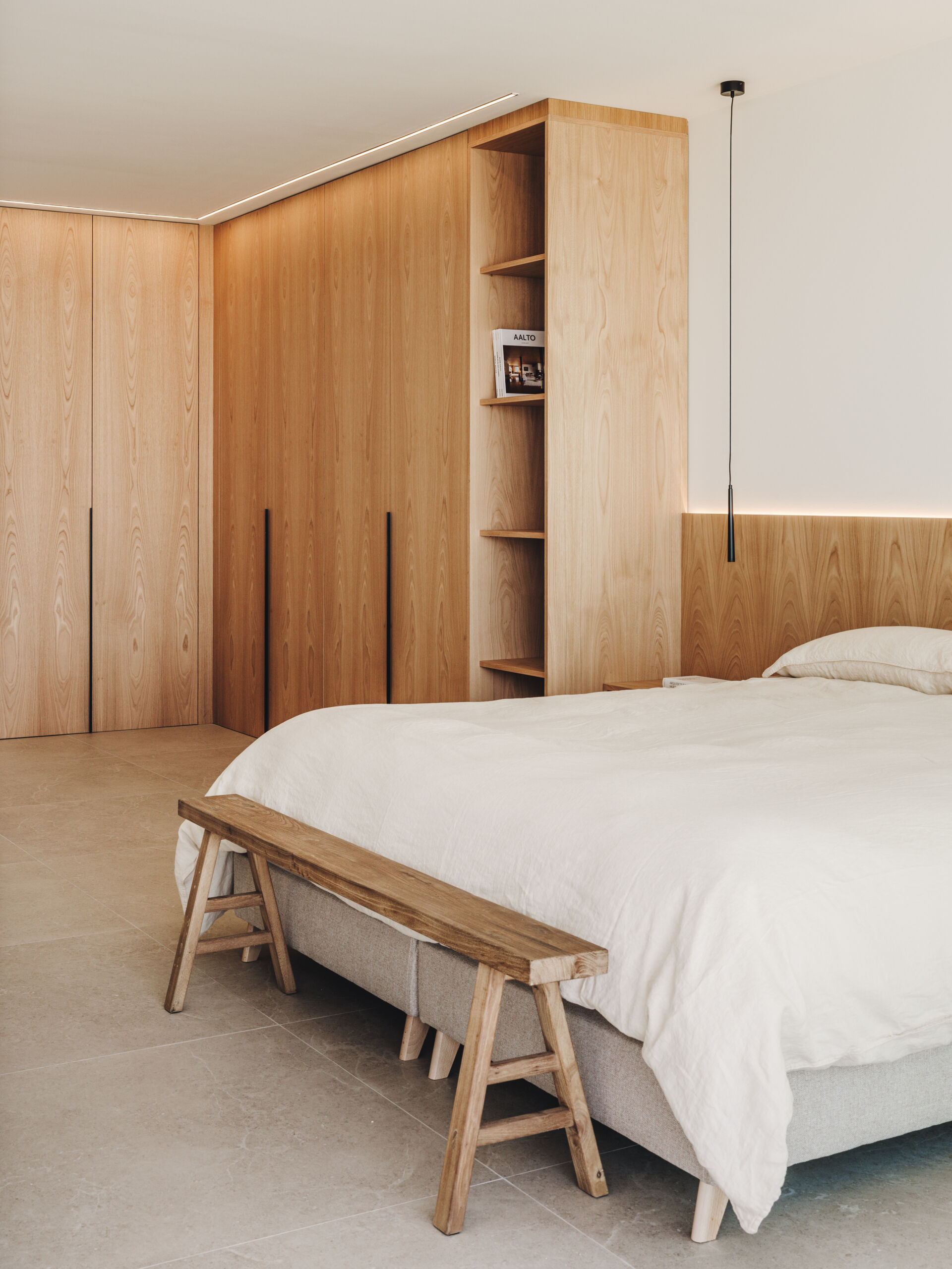 A serene upper-floor bedroom retreat where oak and travertine combine with filtered light and horizon-facing views.