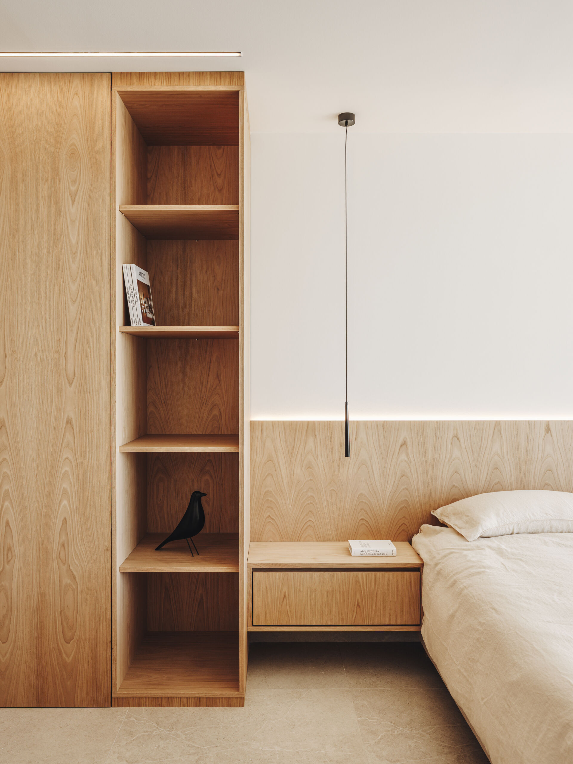 A serene upper-floor bedroom retreat where oak and travertine combine with filtered light and horizon-facing views.