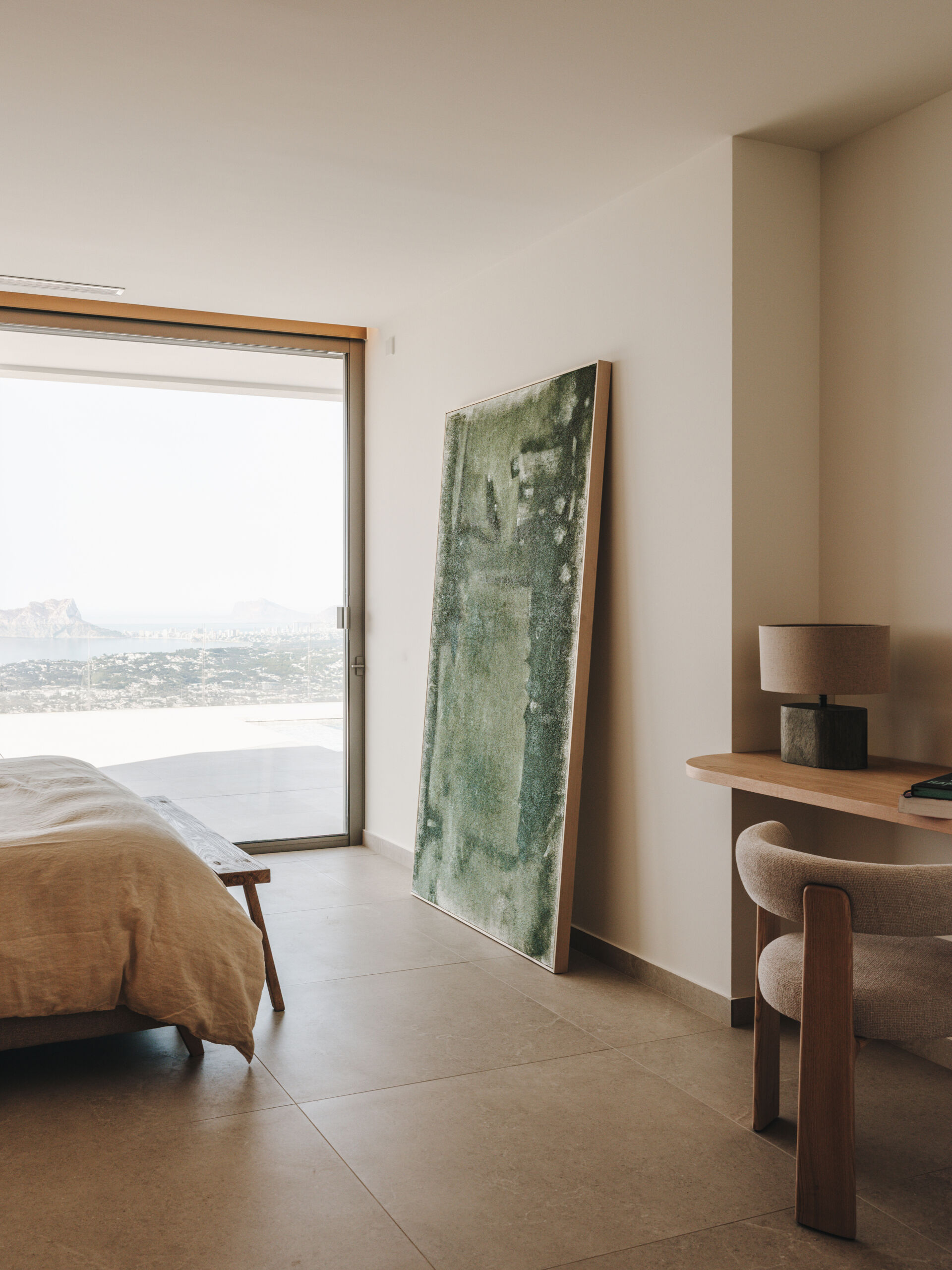 A serene upper-floor bedroom retreat where oak and travertine combine with filtered light and horizon-facing views.