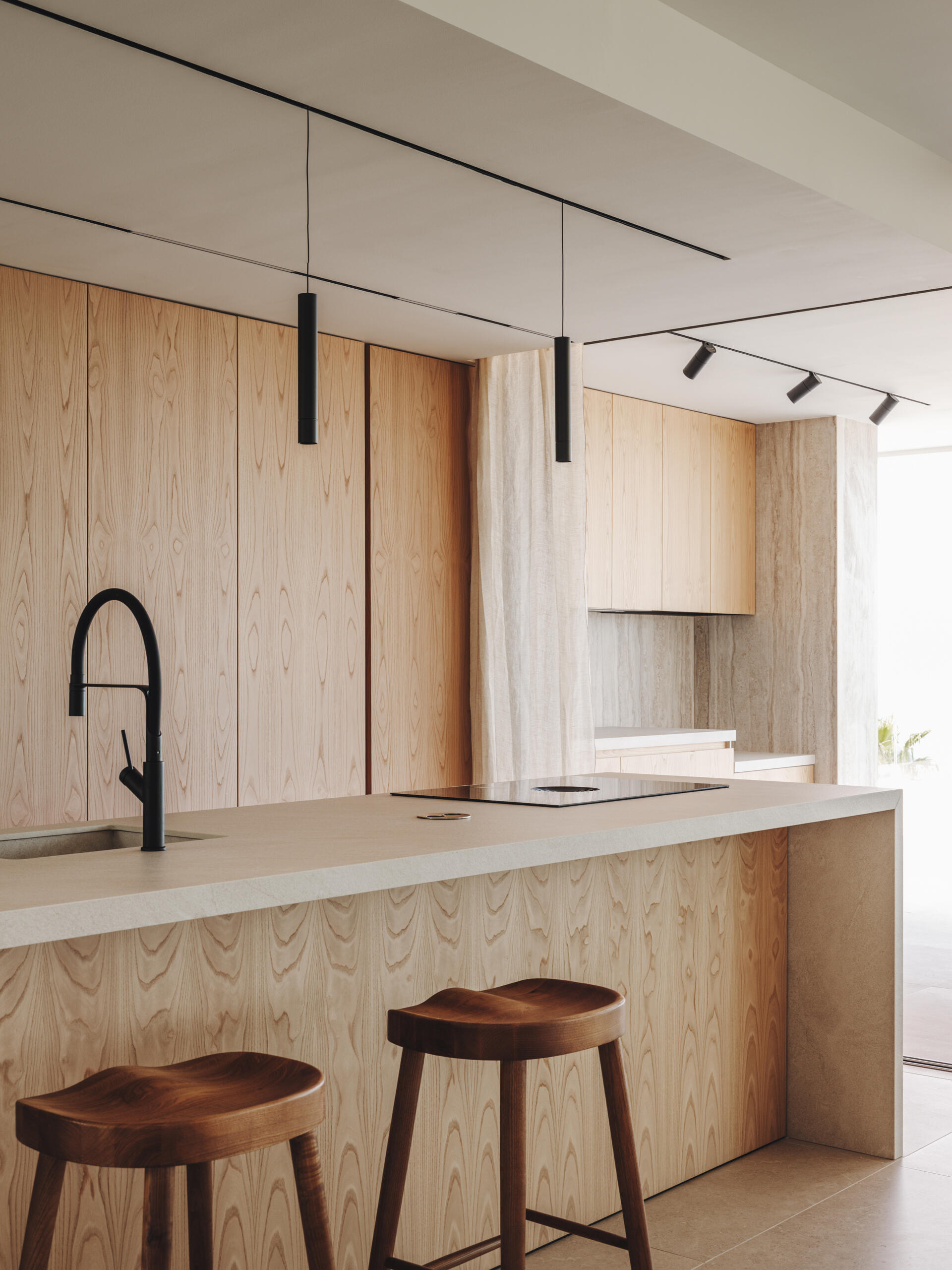 Custom oak cabinetry, integrated lighting, and matching indoor-outdoor finishes define this refined, functional kitchen.