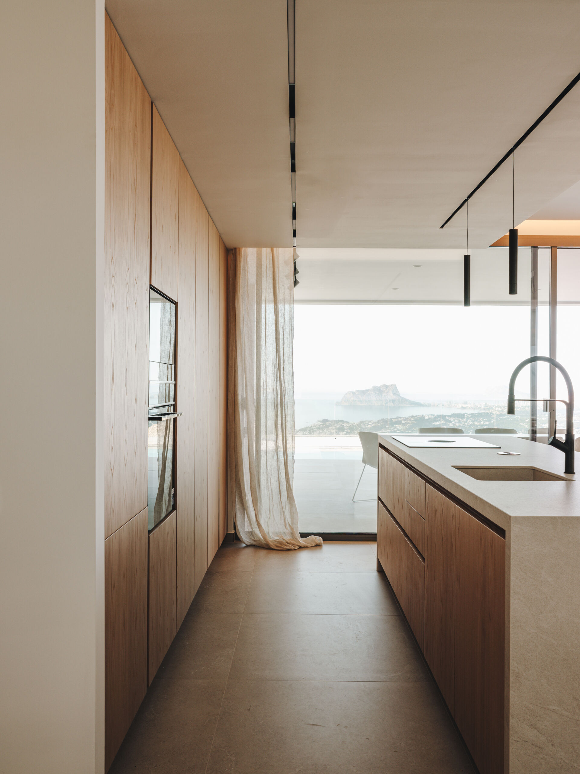 Custom oak cabinetry, integrated lighting, and matching indoor-outdoor finishes define this refined, functional kitchen.