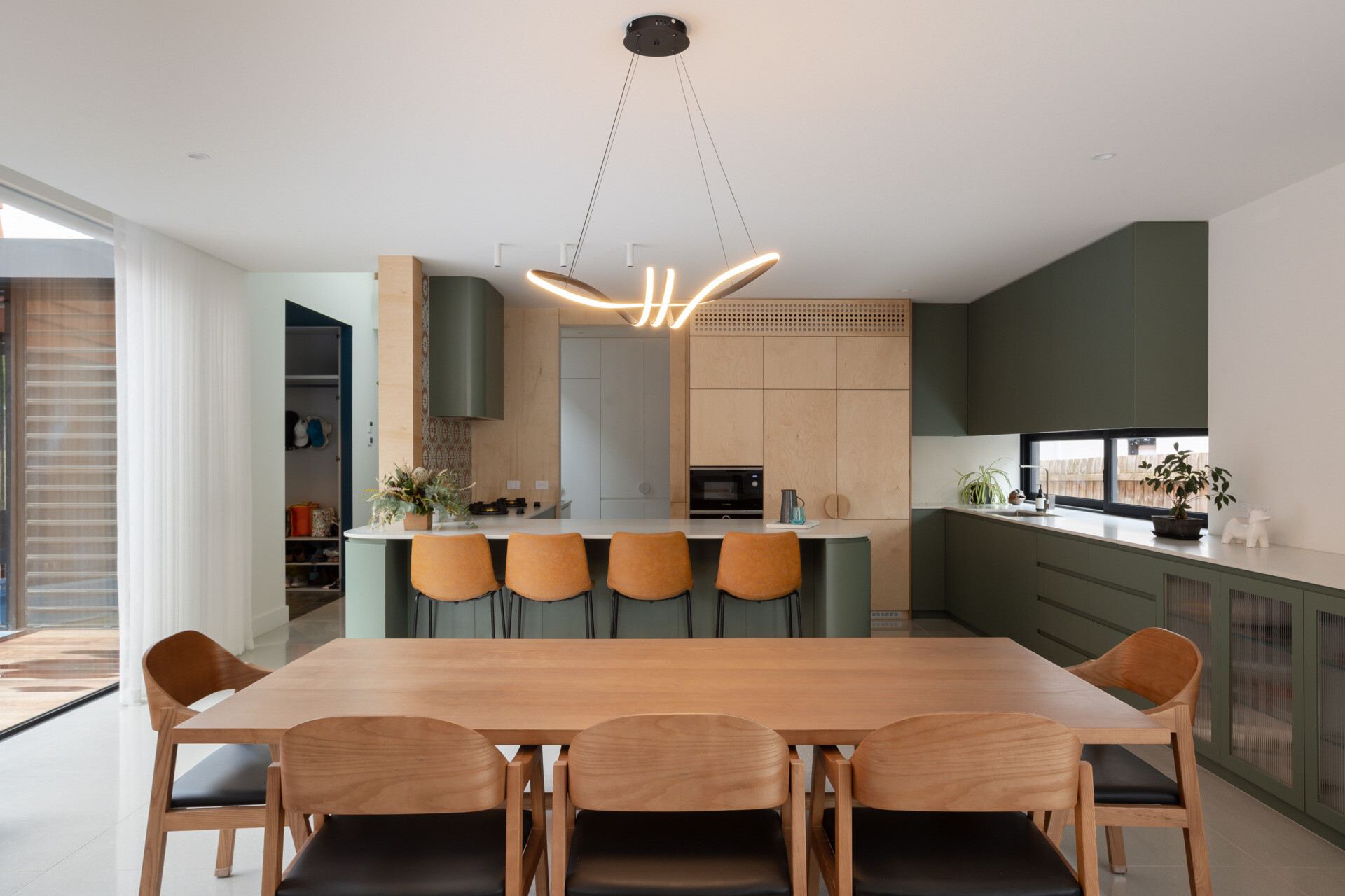 With green and wood joinery, the kitchen and dining area continue the home’s natural material palette. These spaces are active and expressive, balancing the energy of daily meals with a calm, tonal foundation. Large openings connect directly to the courtyard, allowing light and breeze to fill the space.