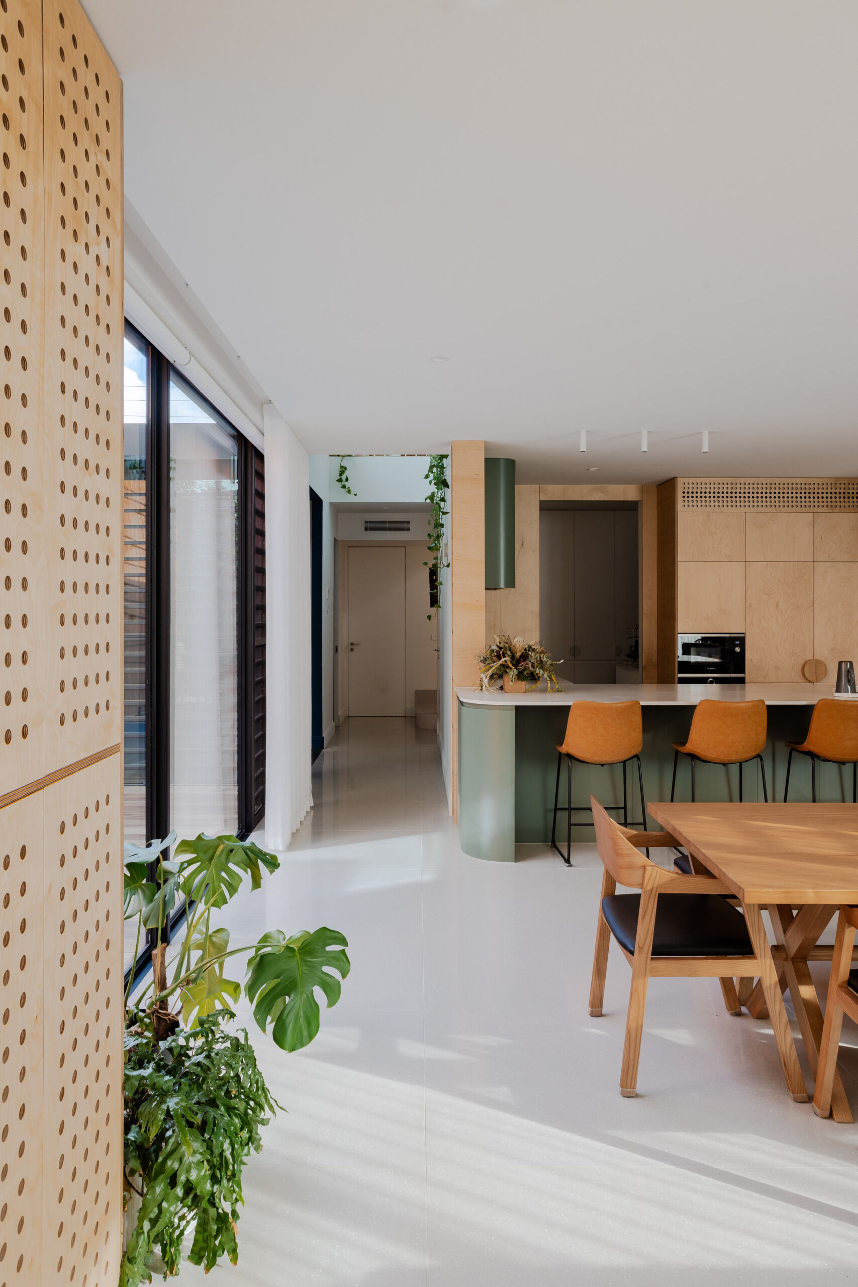 With green and wood joinery, the kitchen and dining area continue the home’s natural material palette. These spaces are active and expressive, balancing the energy of daily meals with a calm, tonal foundation. Large openings connect directly to the courtyard, allowing light and breeze to fill the space.
