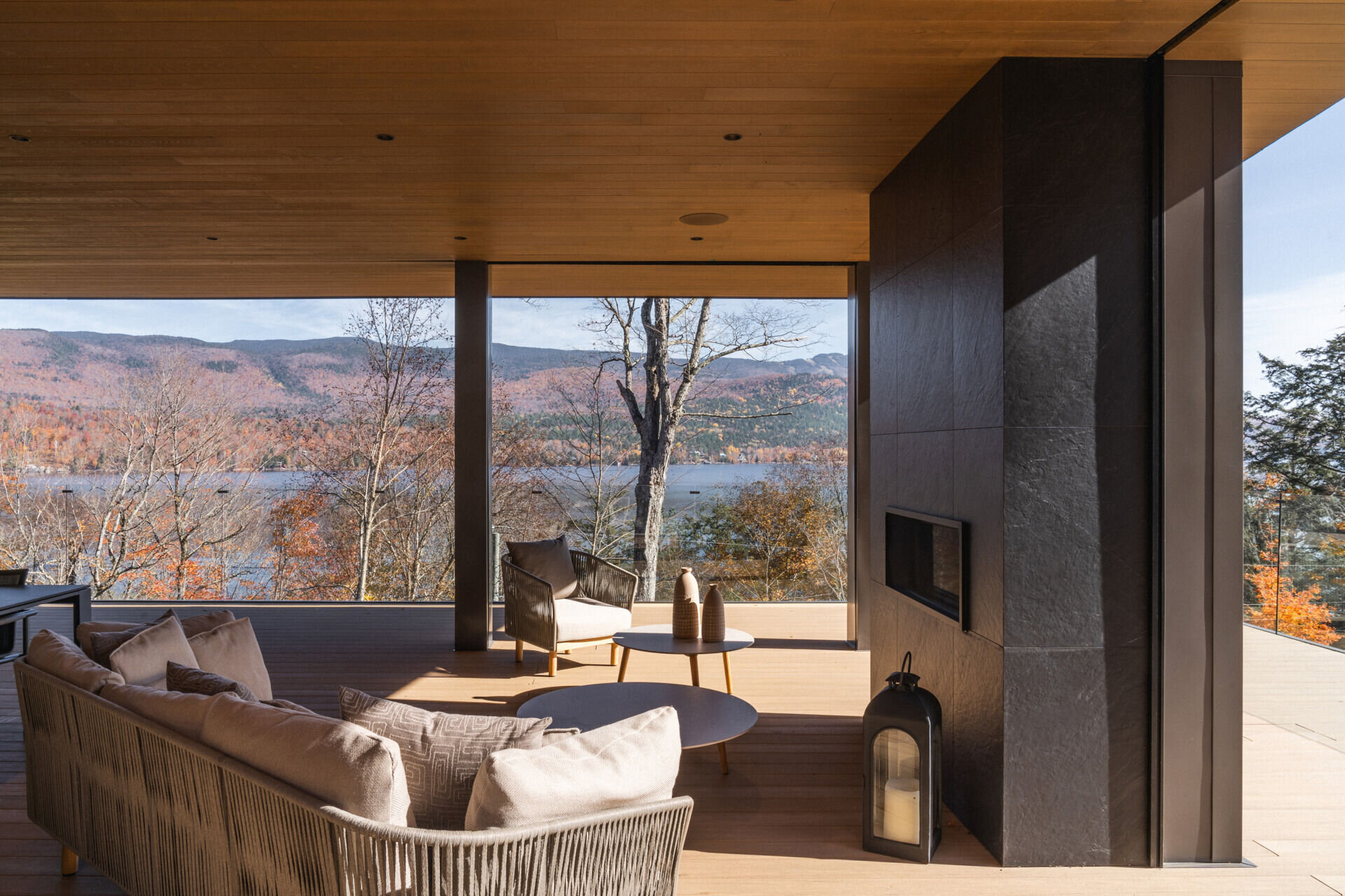 A covered terrace at the entrance is enclosed with retractable insect screens, creating a sheltered space that opens fully to lake views. This area sets the tone for the home's integration of interior comfort with the outdoor setting.