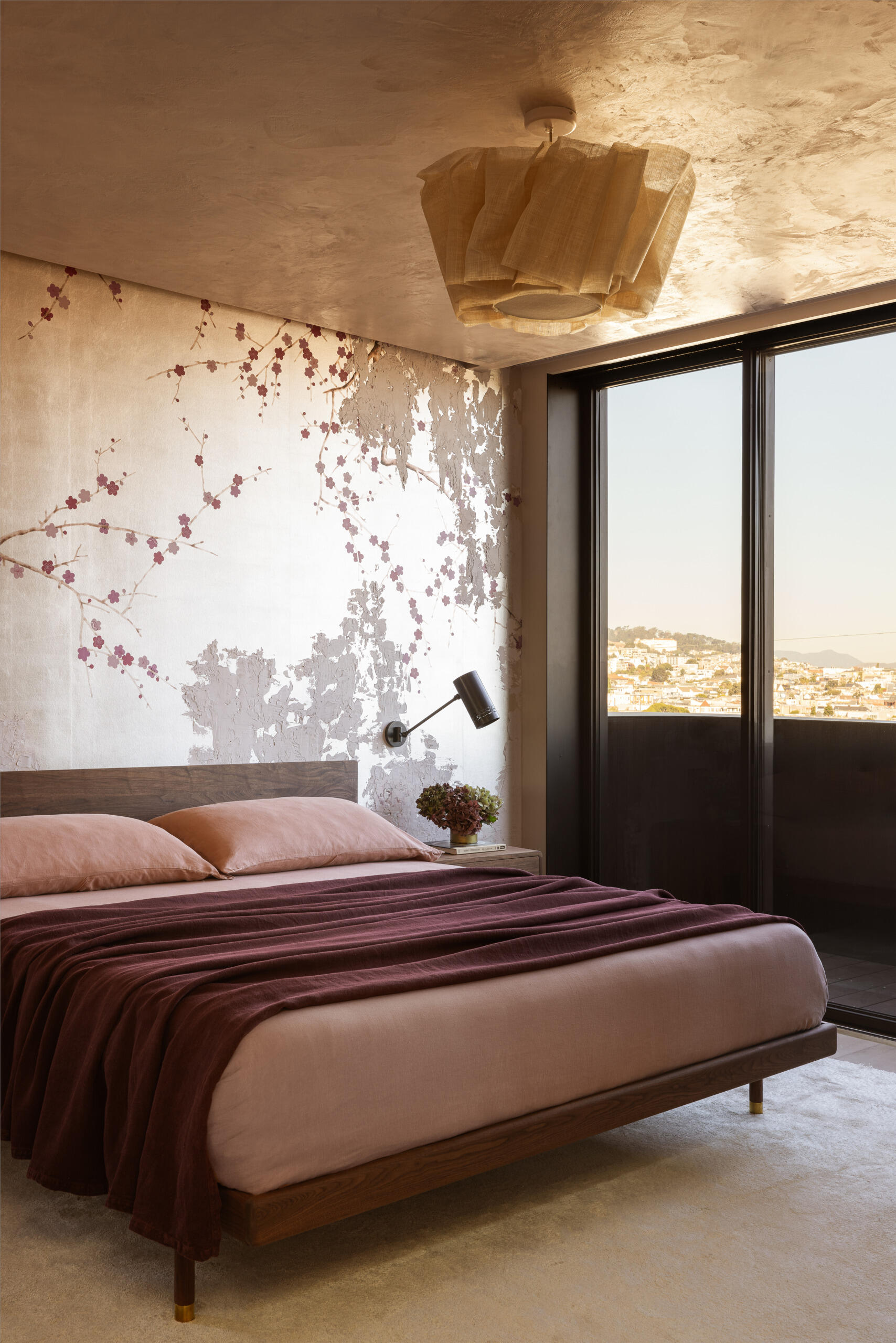 The primary suite blends tactile comfort and tailored design. A Kalon Studios bed, Croft House nightstands, and Commune sconces create a balanced composition, while a floral de Gournay wallcovering lends softness and visual depth.