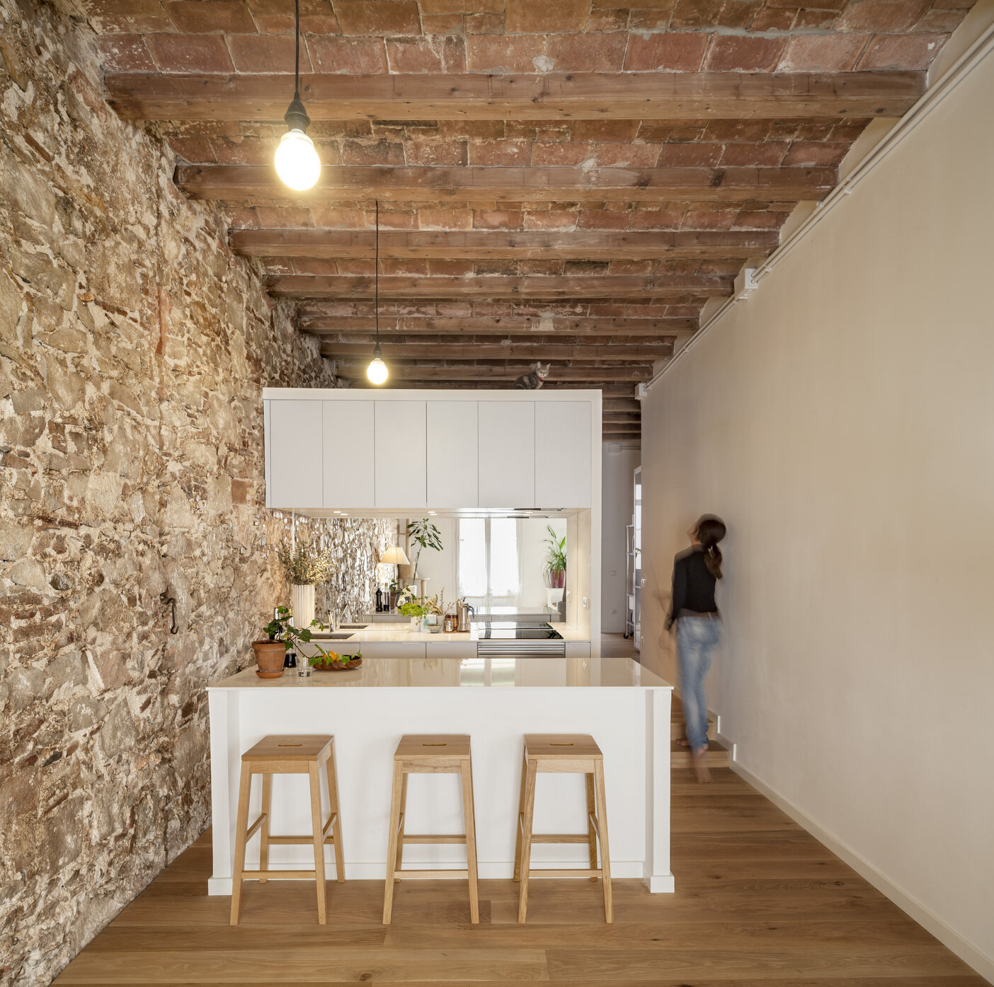 A serene, Japanese-inspired Barcelona apartment that blends stone walls, natural oak, soft light, and open-plan living.