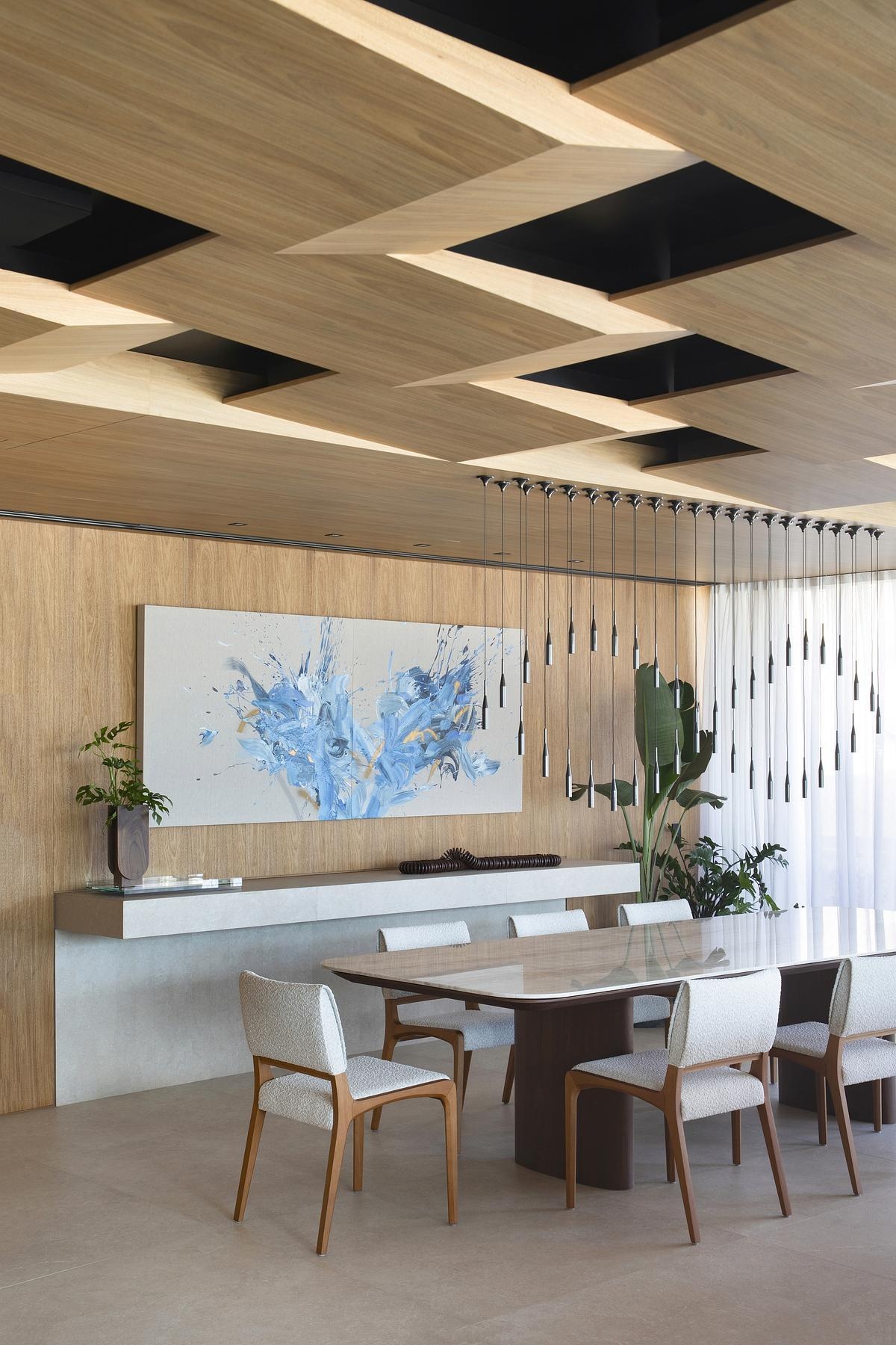 A custom dining table with a Taj Mahal Quartzite top sits beneath 40 floating pendant lights, creating an airy, sculptural centerpiece for gatherings.