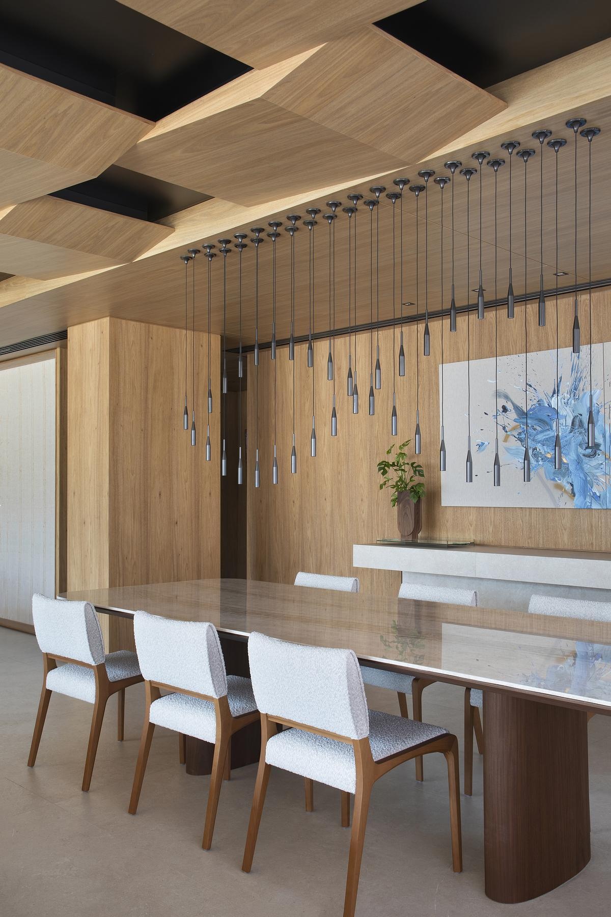 A custom dining table with a Taj Mahal Quartzite top sits beneath 40 floating pendant lights, creating an airy, sculptural centerpiece for gatherings.