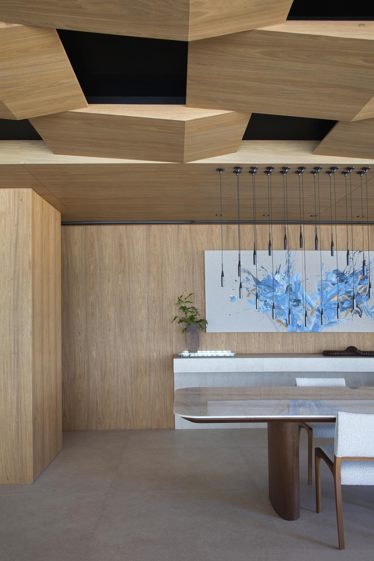 A custom dining table with a Taj Mahal Quartzite top sits beneath 40 floating pendant lights, creating an airy, sculptural centerpiece for gatherings.