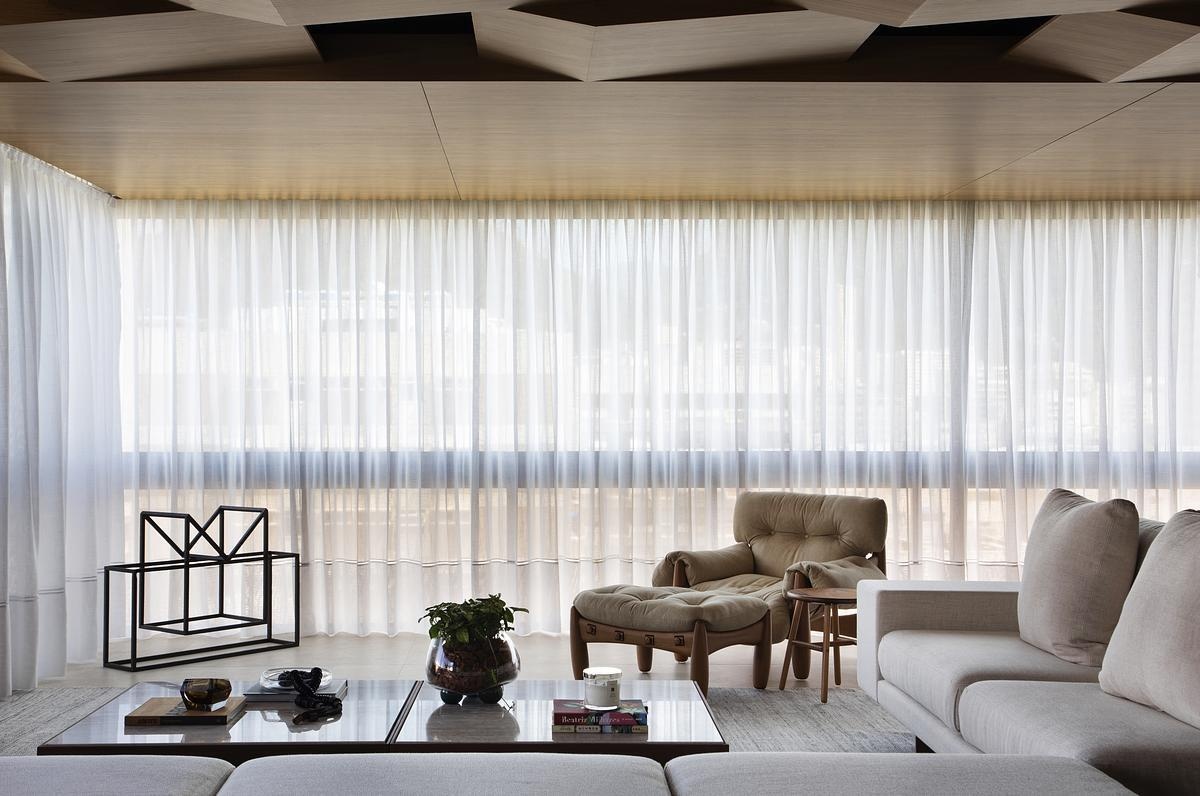 This geometric wood ceiling in an open plan apartment interior transforms structural necessity into a standout design feature, blending texture with hidden functionality.