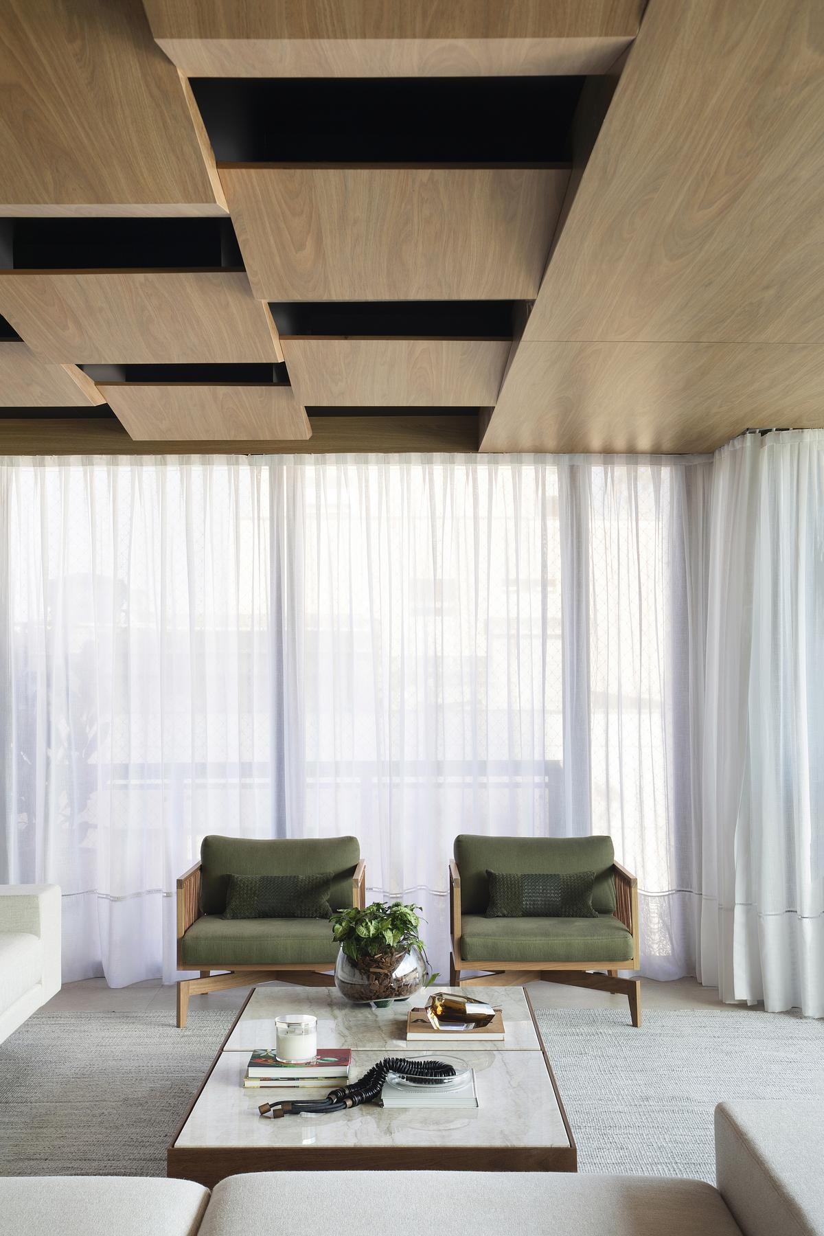 This geometric wood ceiling in an open plan apartment interior transforms structural necessity into a standout design feature, blending texture with hidden functionality.