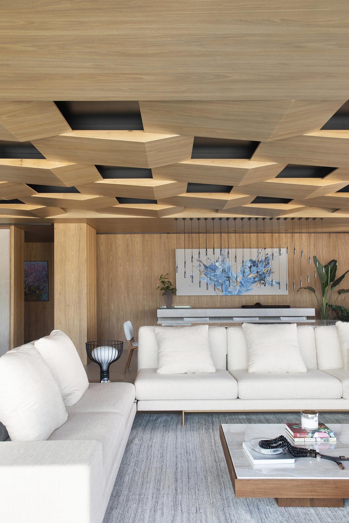 This geometric wood ceiling in an open plan apartment interior transforms structural necessity into a standout design feature, blending texture with hidden functionality.