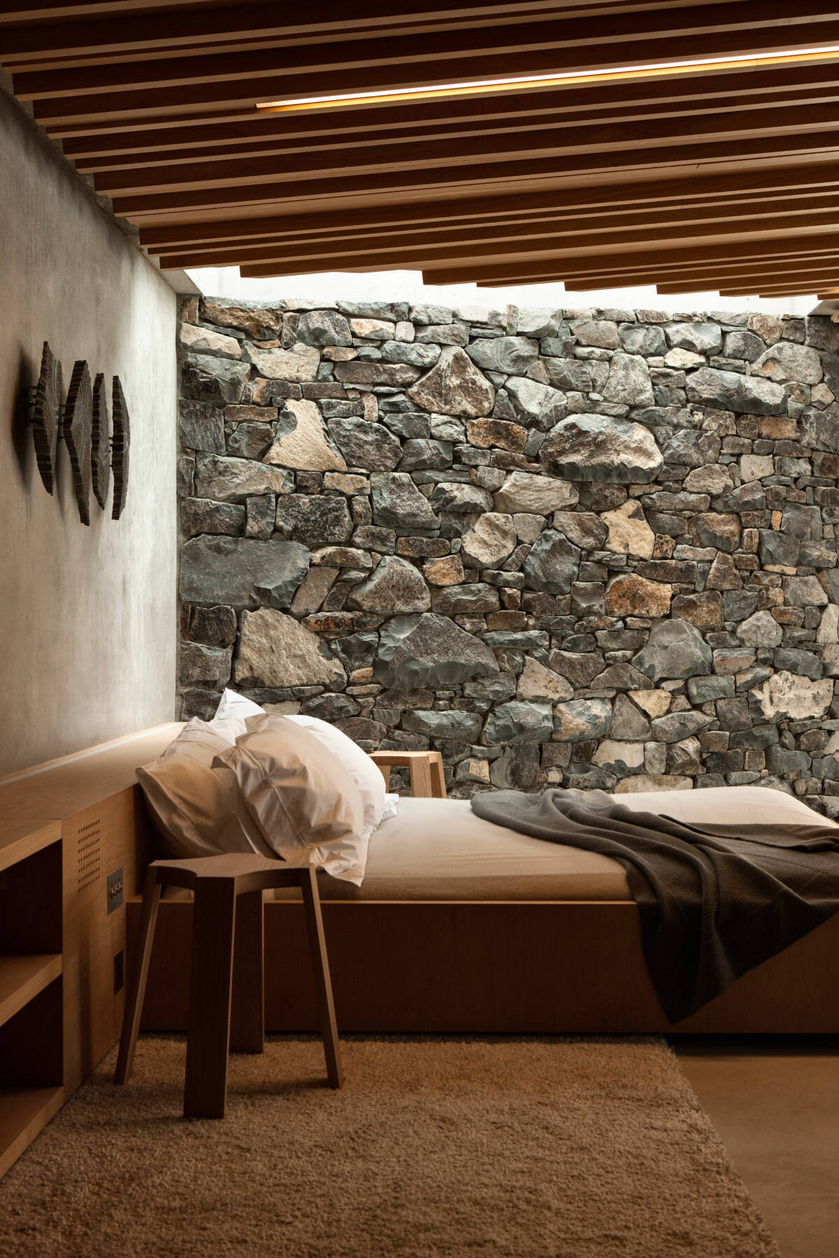 The sleeping area shares the open-plan living space, facing the ocean with nothing to distract. Timber walls and built-in joinery create a warm, cocoon-like feel with room to breathe.