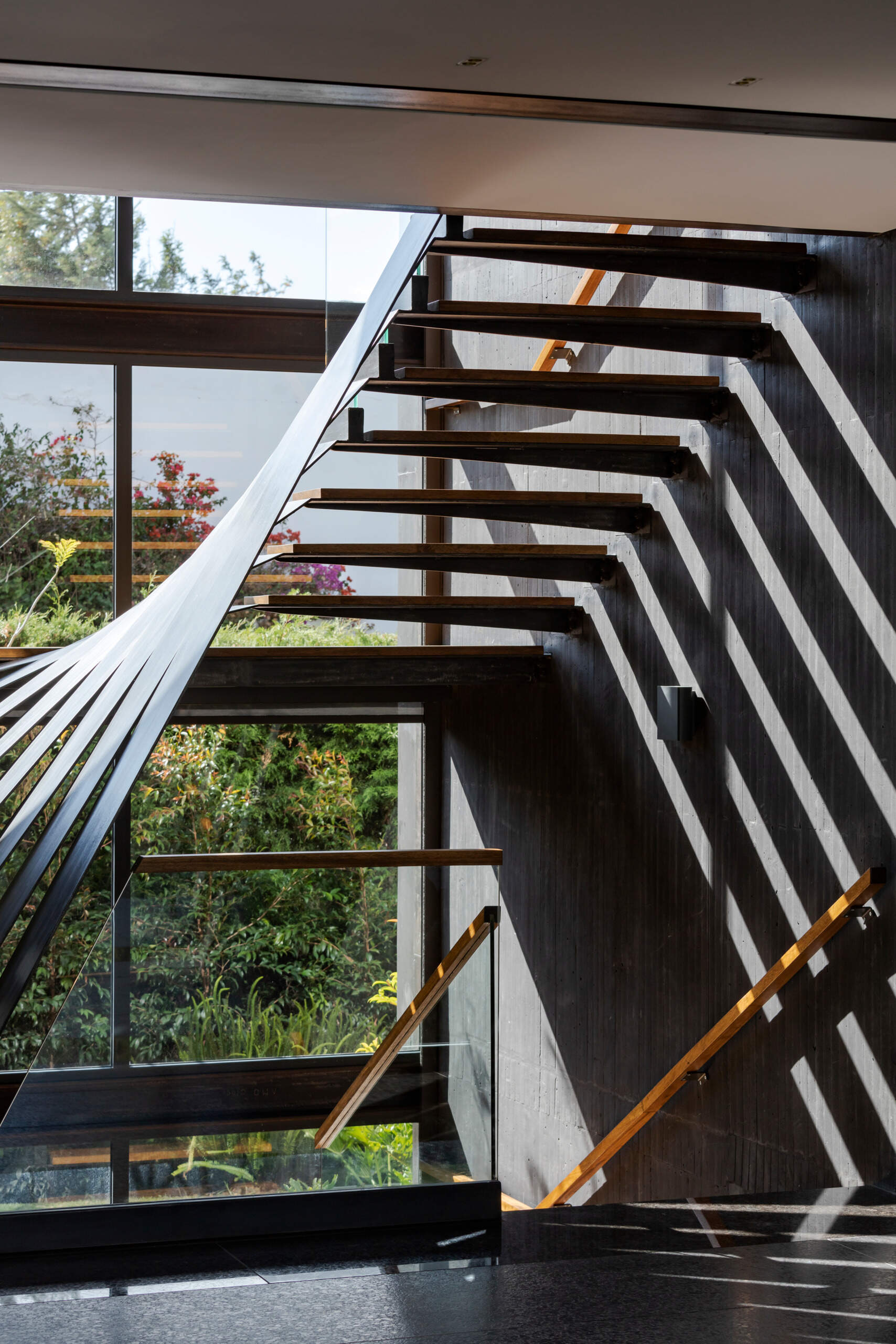 Encased in black-tinted concrete, the stairwell feels like a carved void. It adds depth and drama to the home’s interior while connecting its three levels.