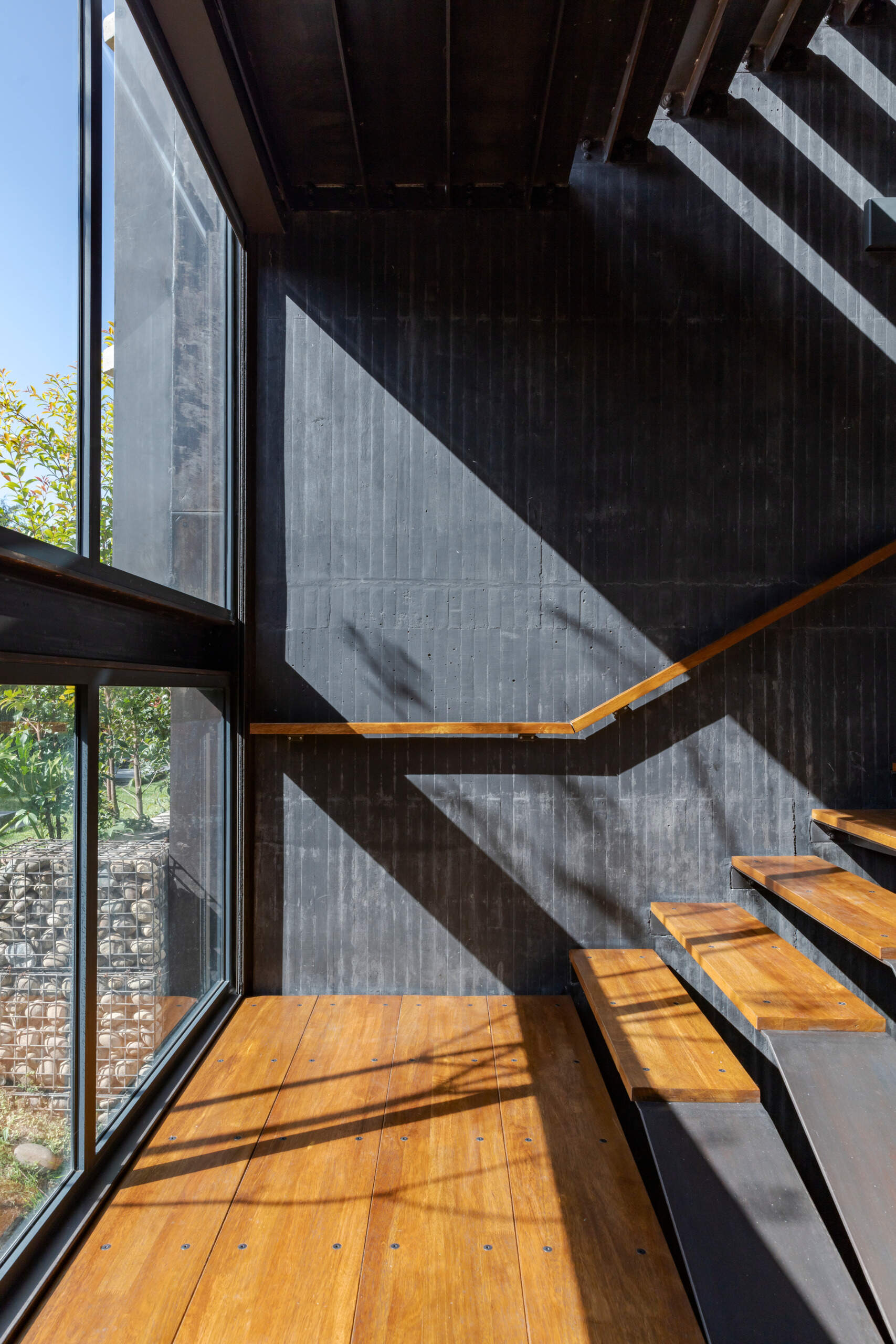 Encased in black-tinted concrete, the stairwell feels like a carved void. It adds depth and drama to the home’s interior while connecting its three levels.