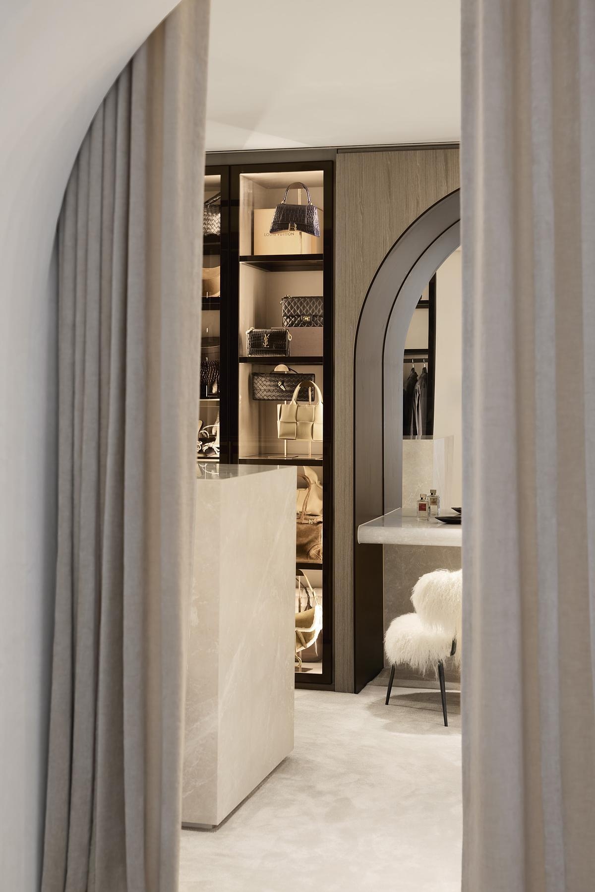 The primary suite evokes soft escape, with sandy tones, travertine finishes, and iconic furnishings like the Eames Lounge Chair. A fireplace and walk-in robe complete the space, offering both connection and privacy.