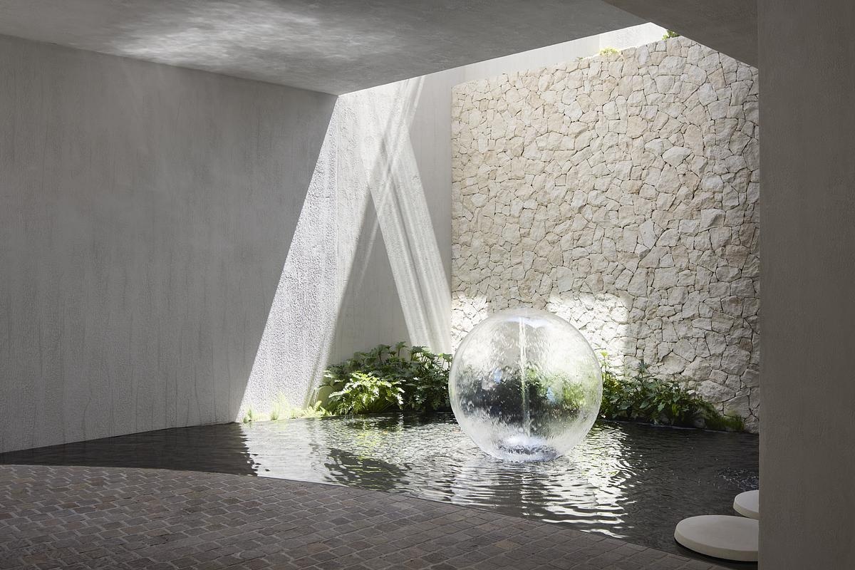 Natural rock cladding, curved forms, and expansive glazing define the sculptural exterior of this serene, modern Melbourne home.