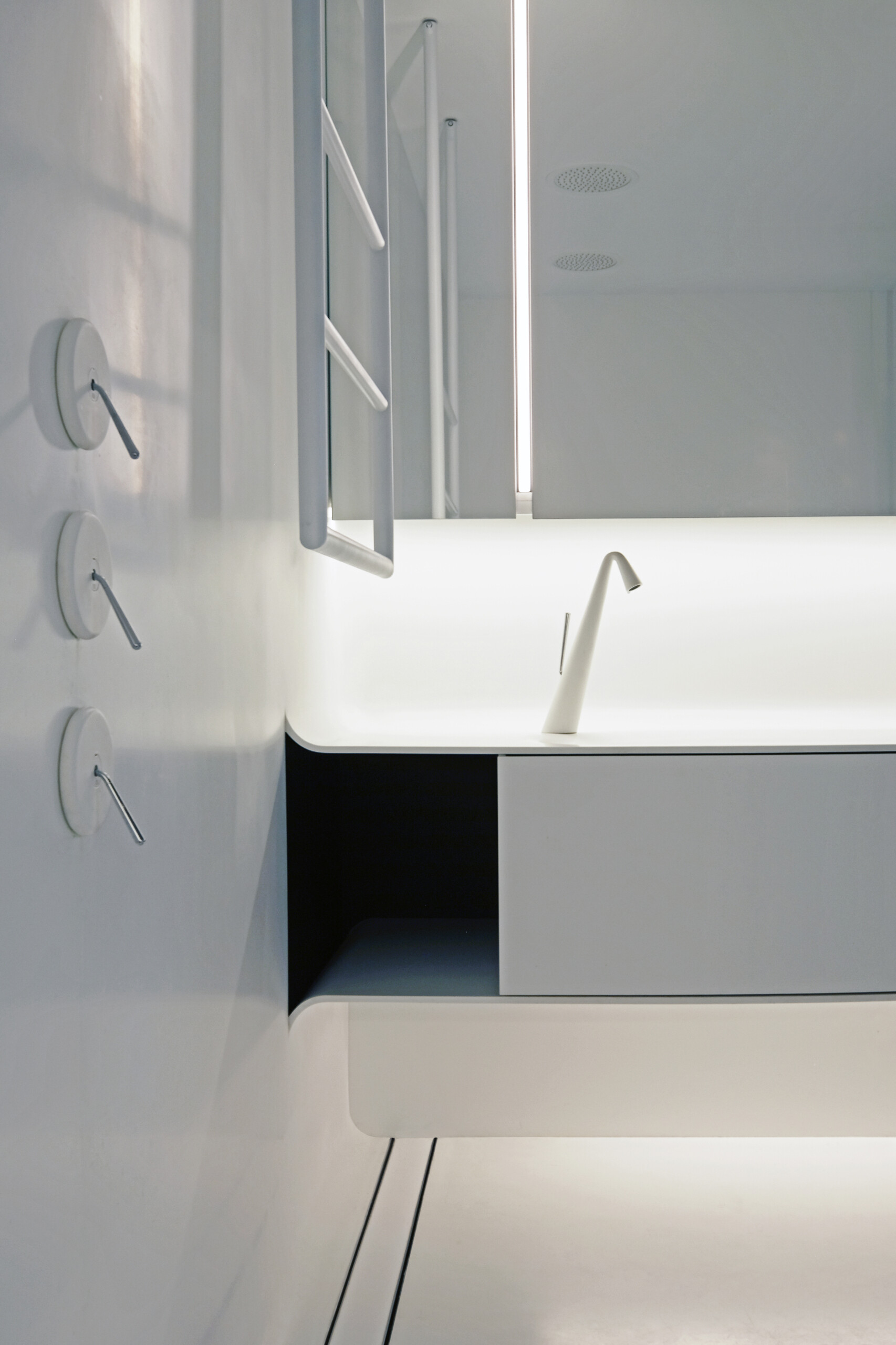 Crisp white finishes and seamless cabinetry give this bathroom a pared-back, contemporary feel. A floating double vanity and sculptural tapware reinforce the clean lines, while concealed lighting adds a soft, ambient glow. A timber door introduces warmth, offering a quiet contrast to the otherwise minimal palette.