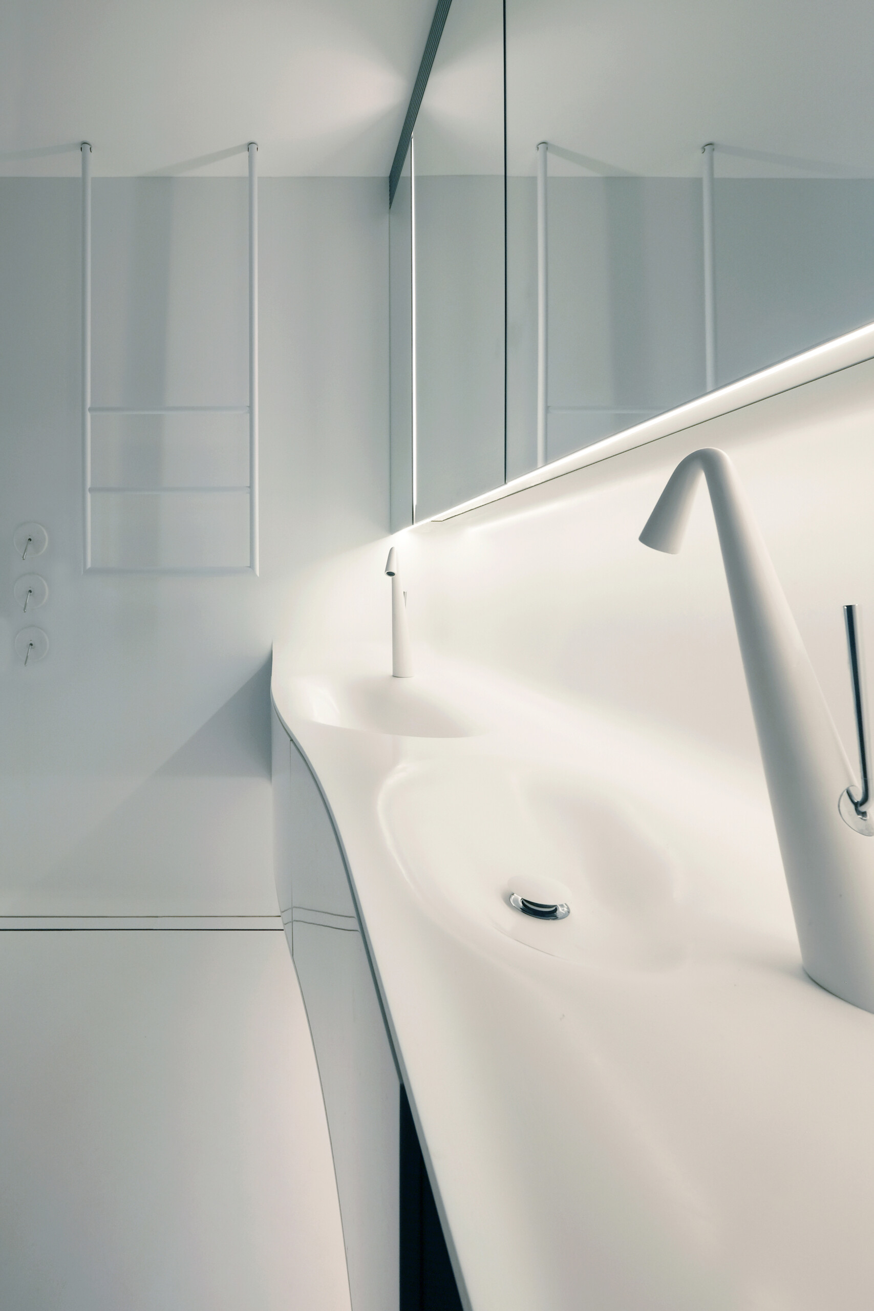 Crisp white finishes and seamless cabinetry give this bathroom a pared-back, contemporary feel. A floating double vanity and sculptural tapware reinforce the clean lines, while concealed lighting adds a soft, ambient glow. A timber door introduces warmth, offering a quiet contrast to the otherwise minimal palette.