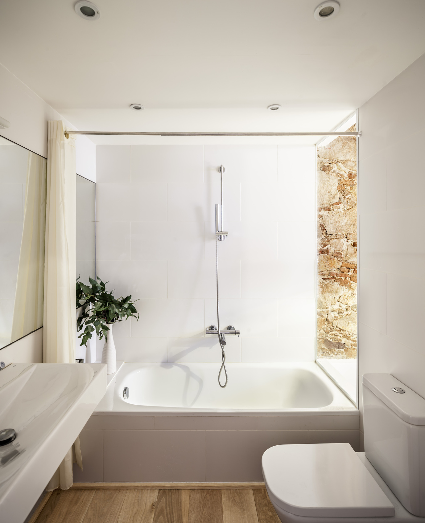 The bathroom features clean lines and a soft connection to the bedroom through an interior window that filters natural light.