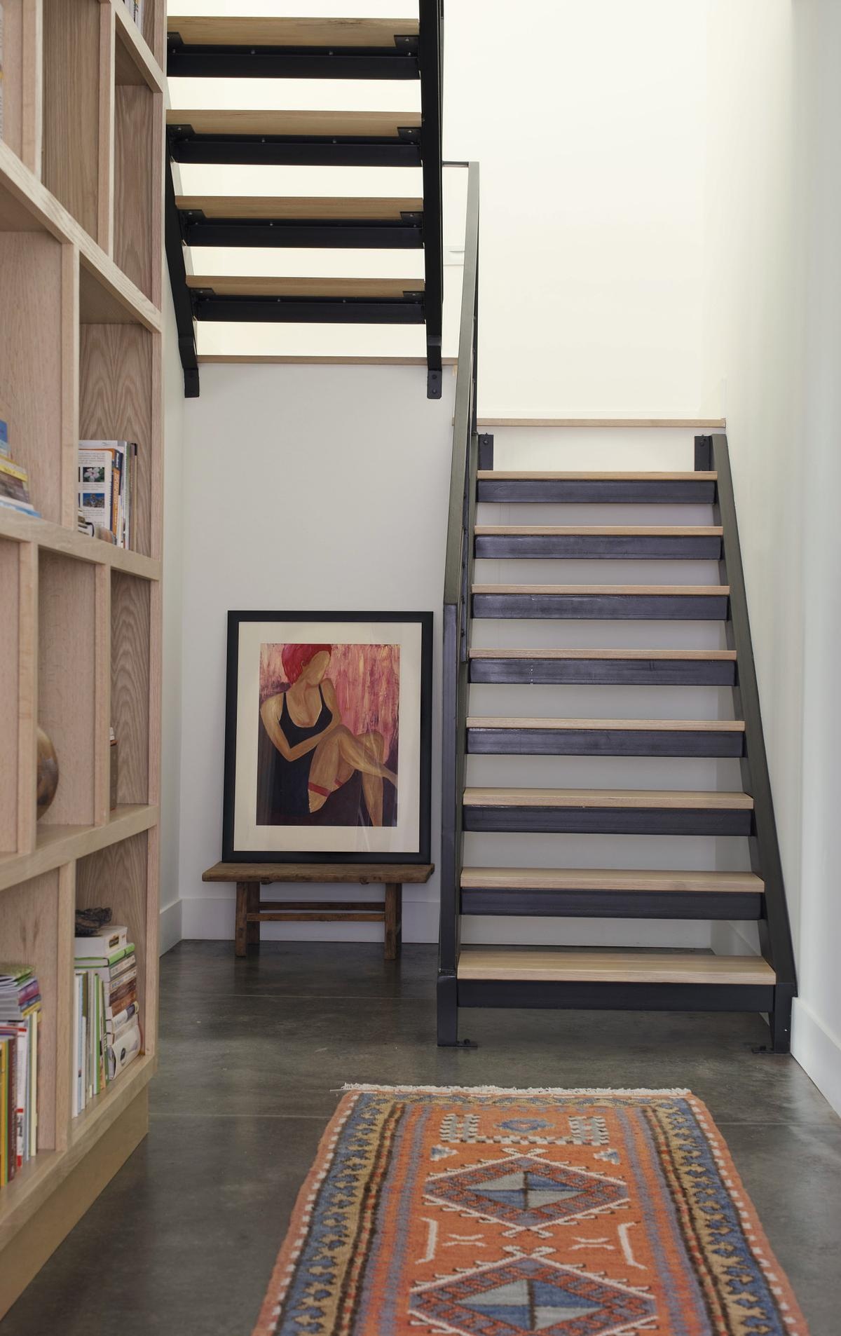 Stairs connect the main living spaces with the basement volume. Their design, using wood and steel, is straightforward and purposeful, supporting ease of movement without distracting from the overall simplicity.
