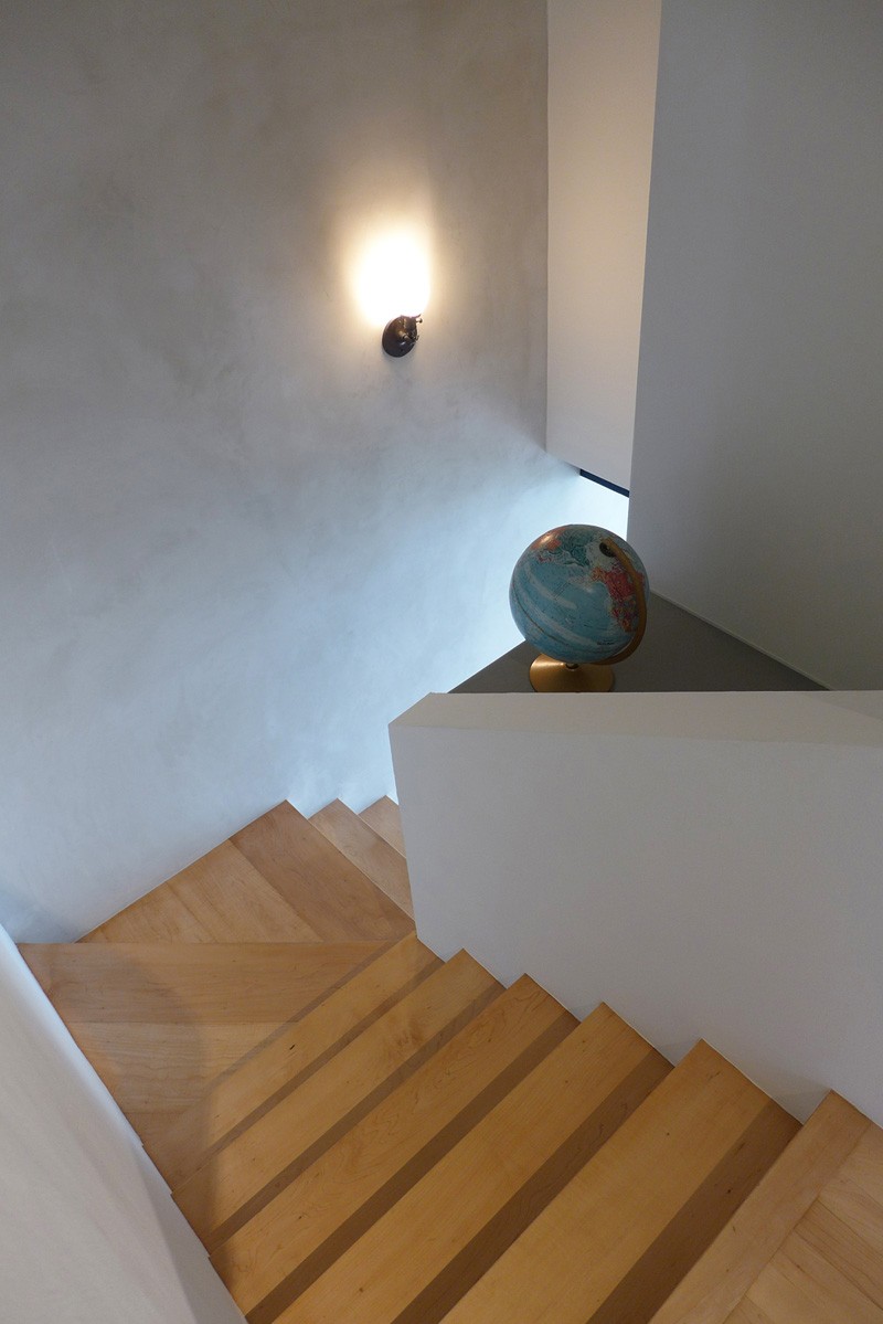 Left untouched, the original stairwell creates a quiet visual pause between the vibrant kitchen and moody upstairs.