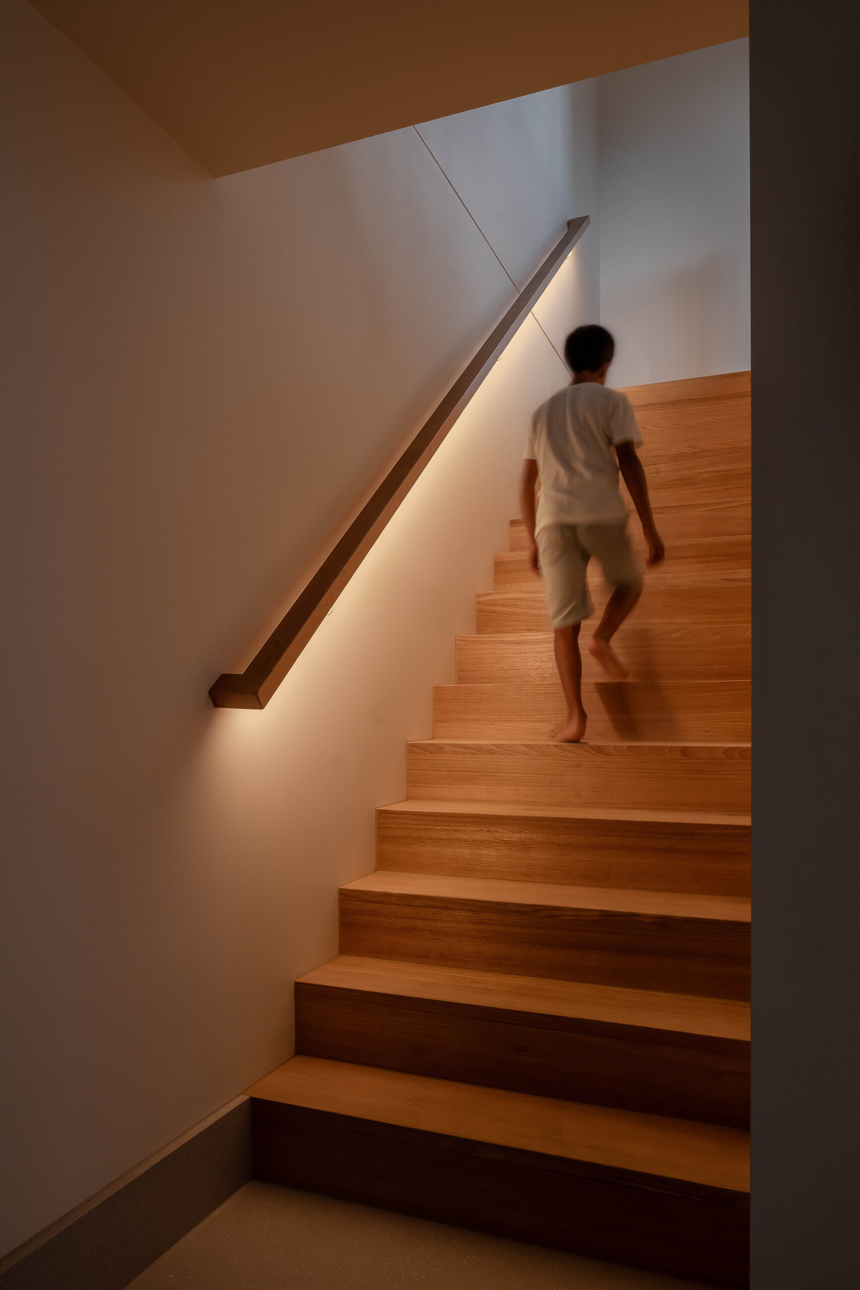 Wood stairs connect the two floors of the home, while hidden lighting has been included in the handrail design.