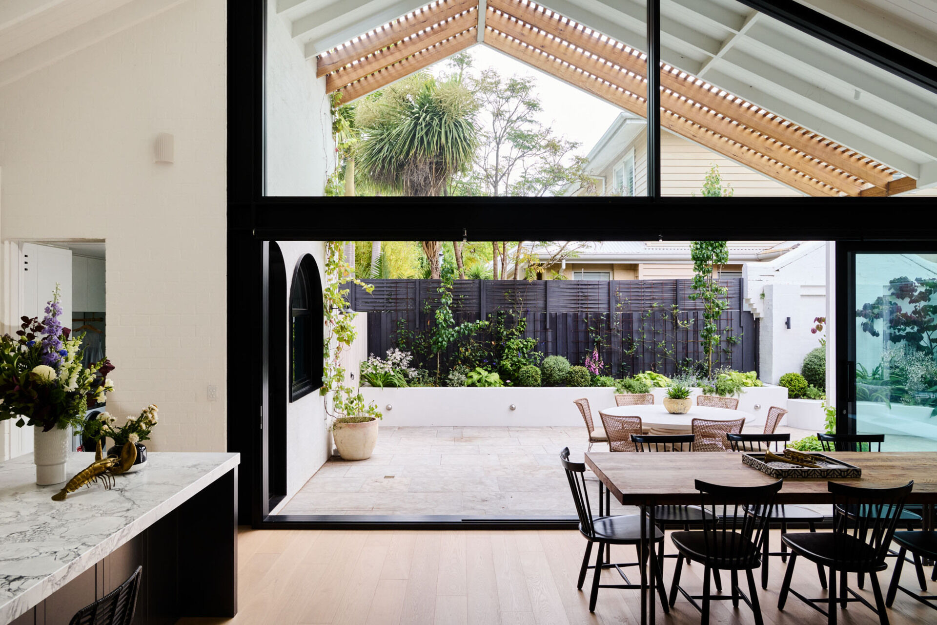 Vaulted ceilings and sliding doors flood this dining area with light. Natural timber furniture and a restrained palette make every meal feel like a retreat.