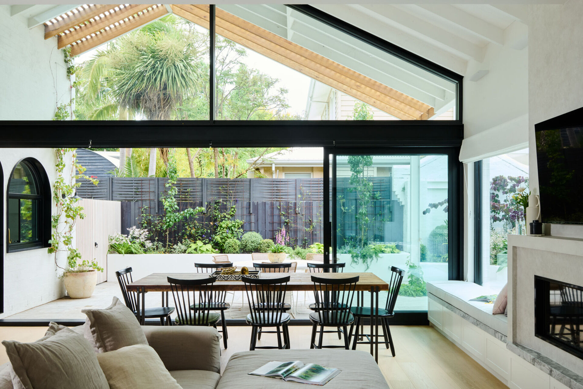 Vaulted ceilings and sliding doors flood this dining area with light. Natural timber furniture and a restrained palette make every meal feel like a retreat.