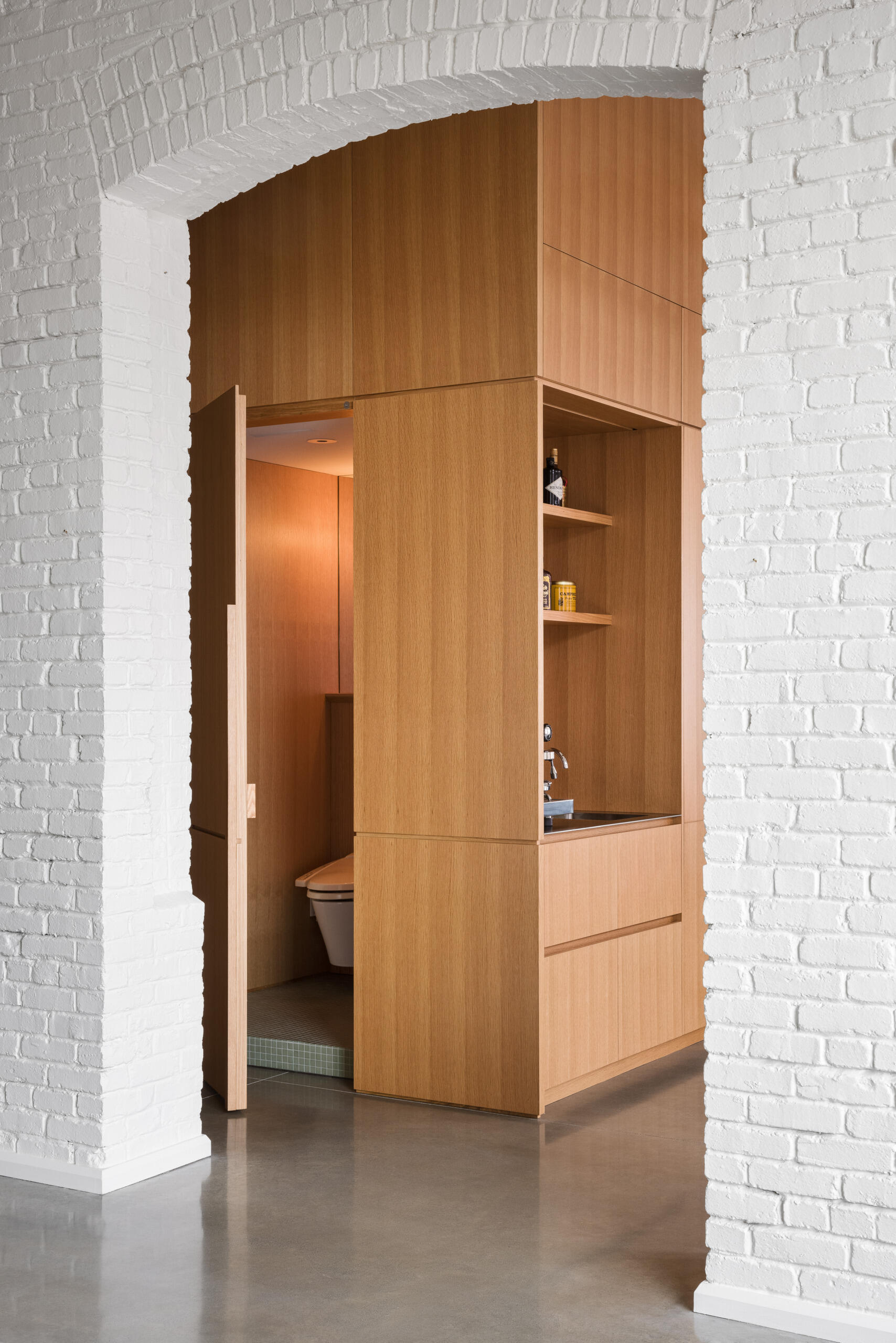 Tucked into a white oak insert, this powder room proves small spaces can still make a statement with thoughtful finishes and seamless integration.